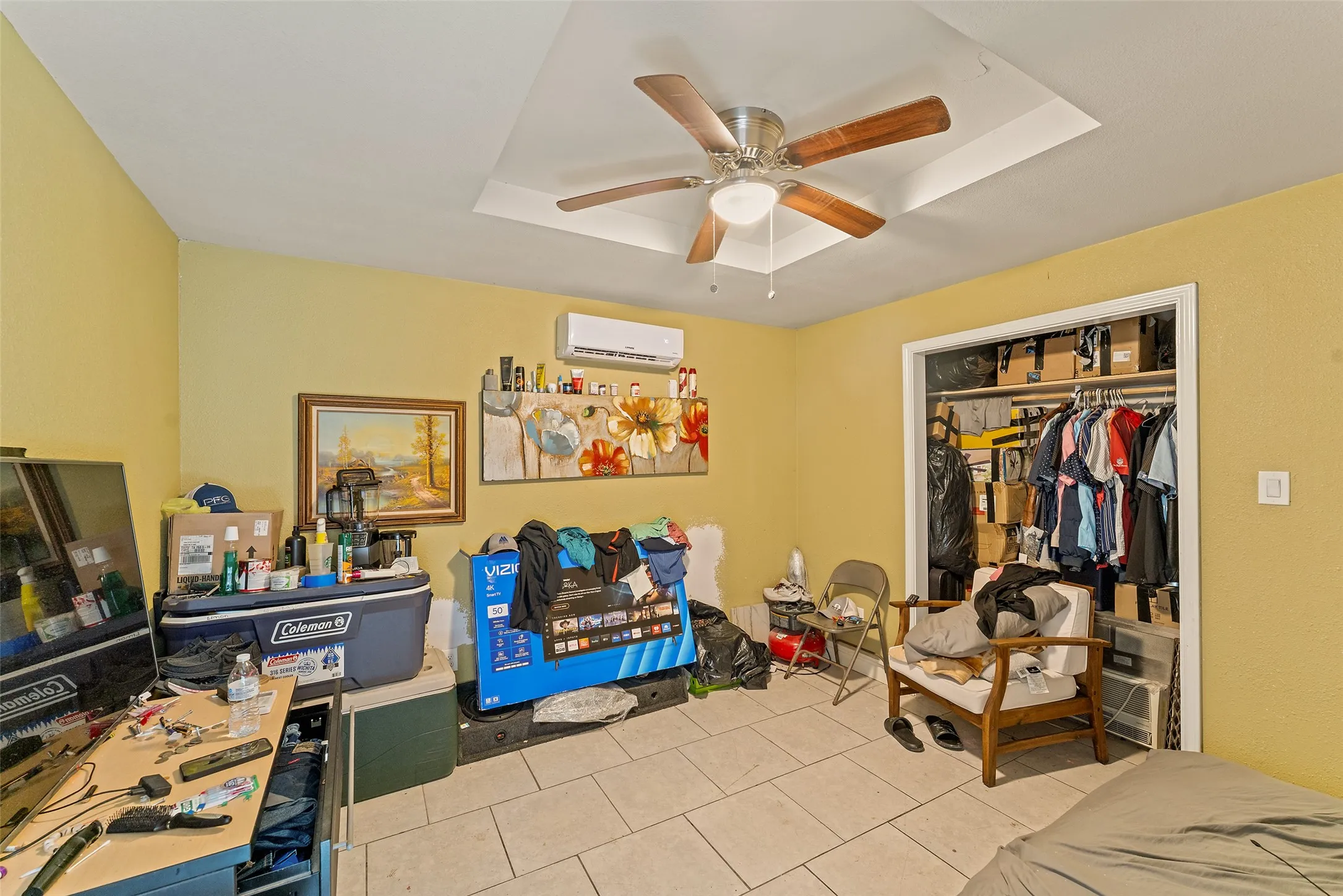 Recessed ceiling with a central fan light fixture, integrated ductless mini-split system, tile flooring, and an open closet with built-in shelving
