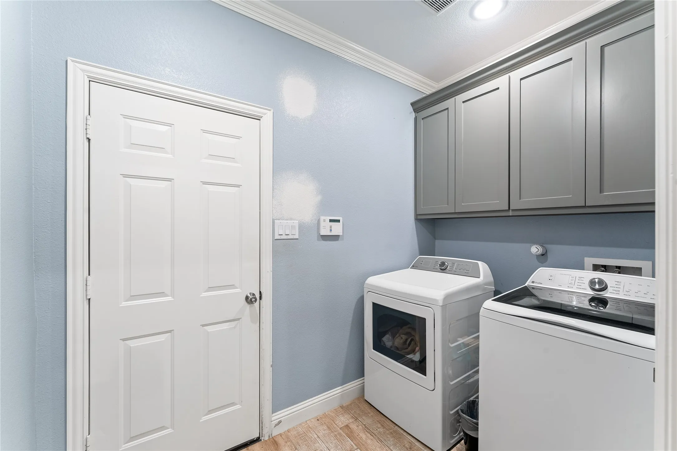 Utility area with wood-finish flooring and crown molding