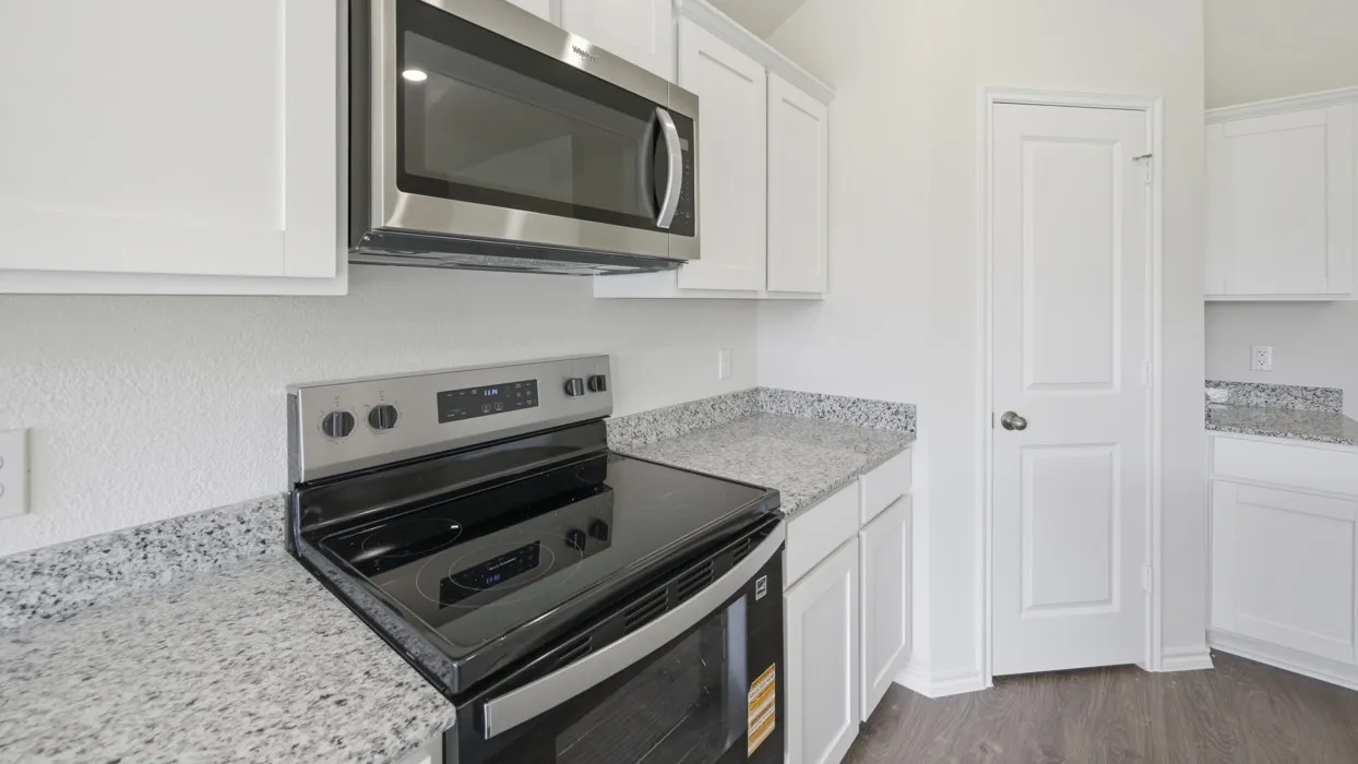 Contemporary kitchen featuring white cabinetry, light speckled countertops, stainless steel microwave, black electric range, and wood-finish flooring