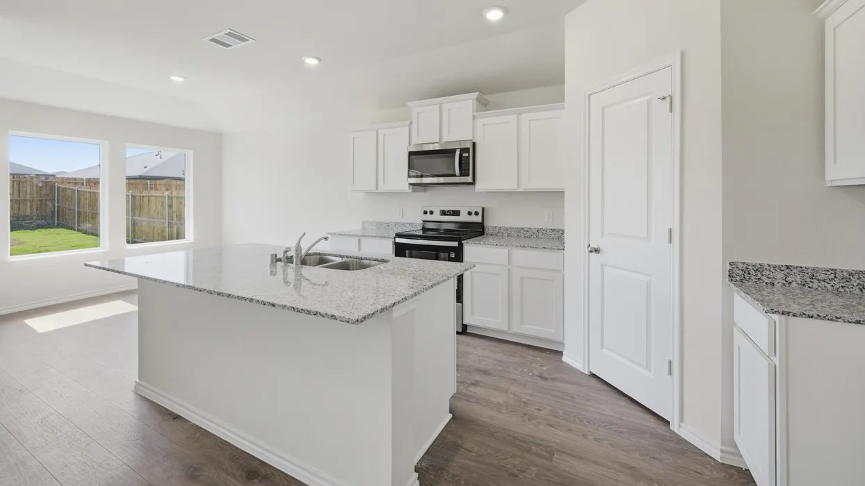 Kitchen featuring an island with double basin sink, white cabinetry, speckled countertops, stainless steel microwave, and wood-finish flooring