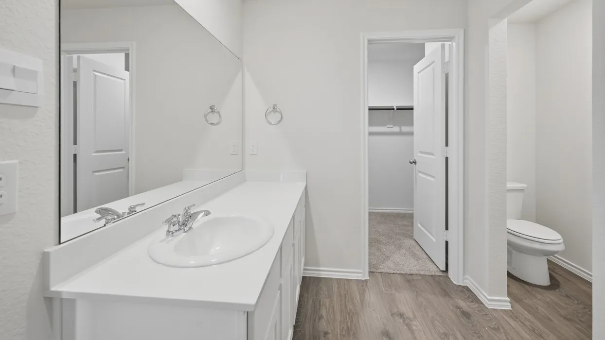 Bathroom featuring a single basin vanity with a white countertop, chrome faucet, and expansive wall-mounted mirror