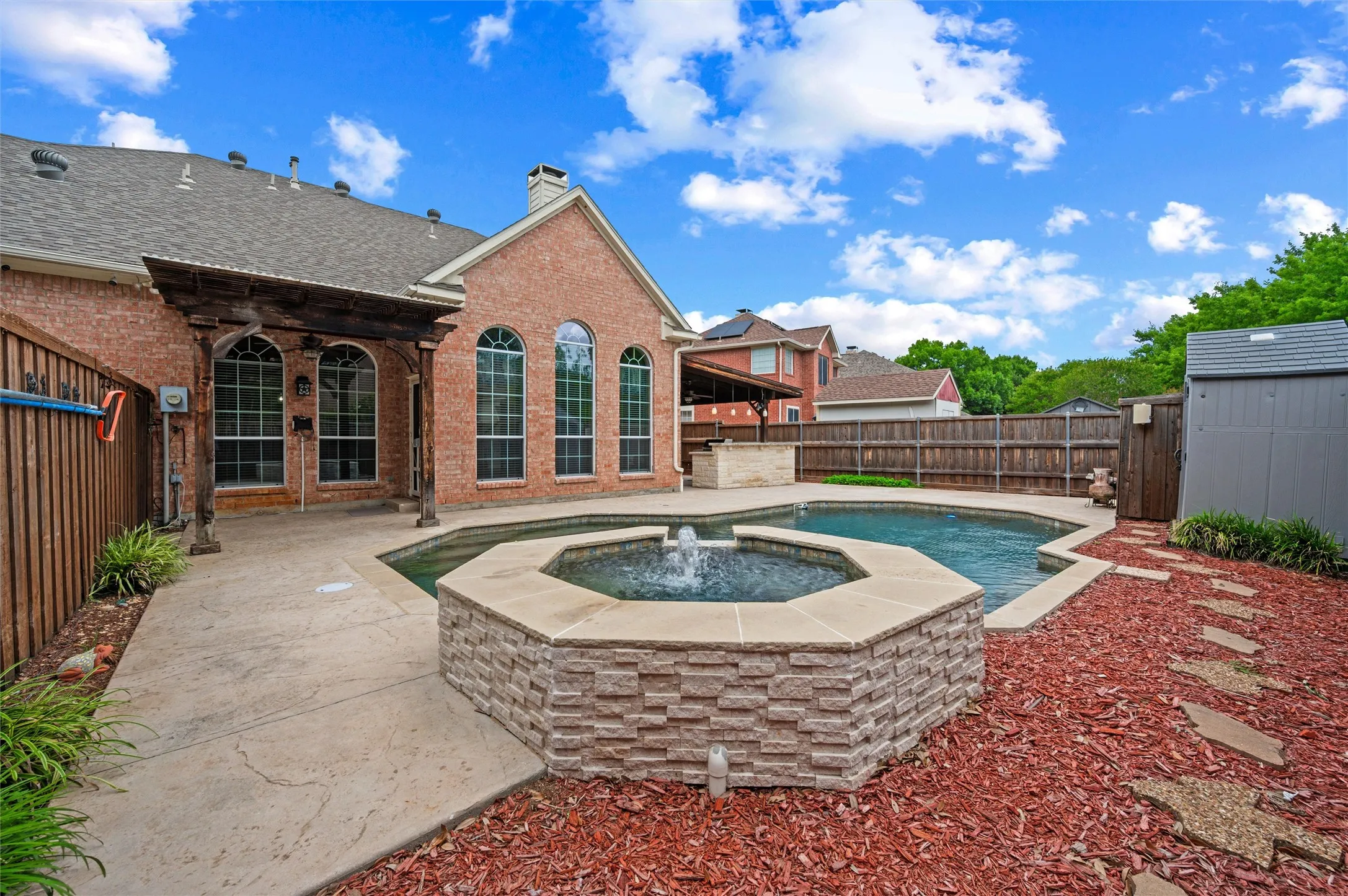 Pebble Tech Pool and attached SPA with waterfall; Stamped Concrete on decking for easy walking; storage shed for pool equipment
