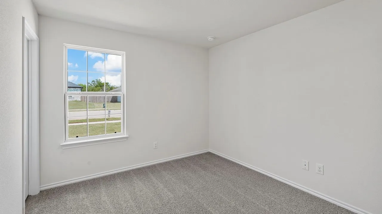 Bright room featuring light gray carpeting, neutral wall finishes, and a framed window providing exterior visibility