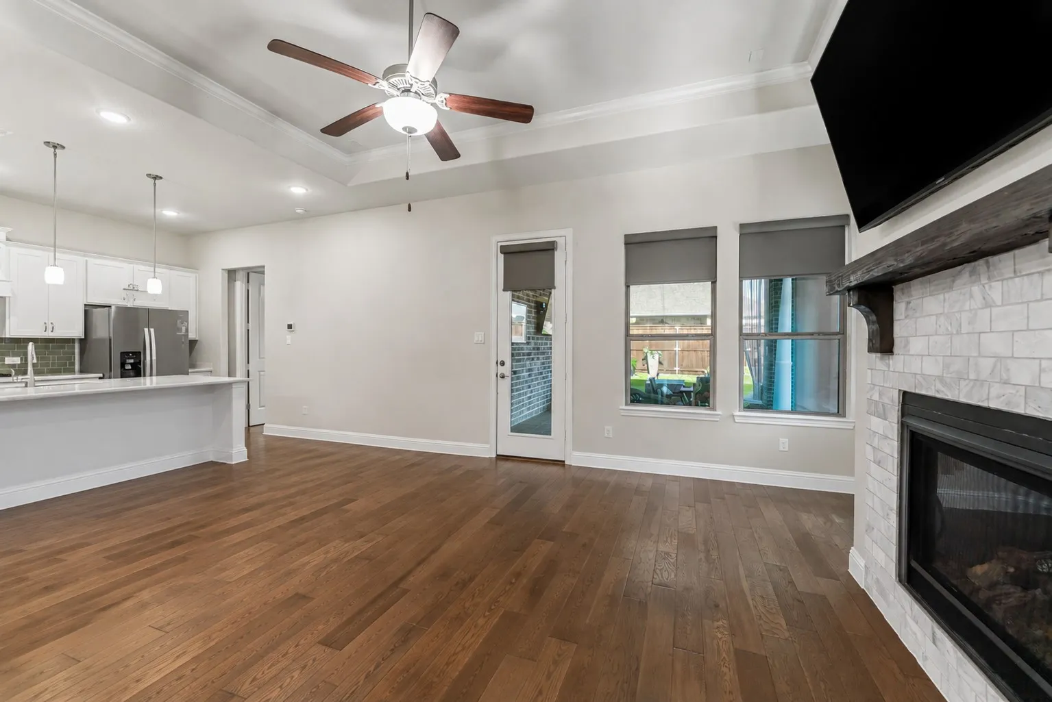 Open family room features hardwood flooring, a gas fireplace, and direct access to the covered patio.