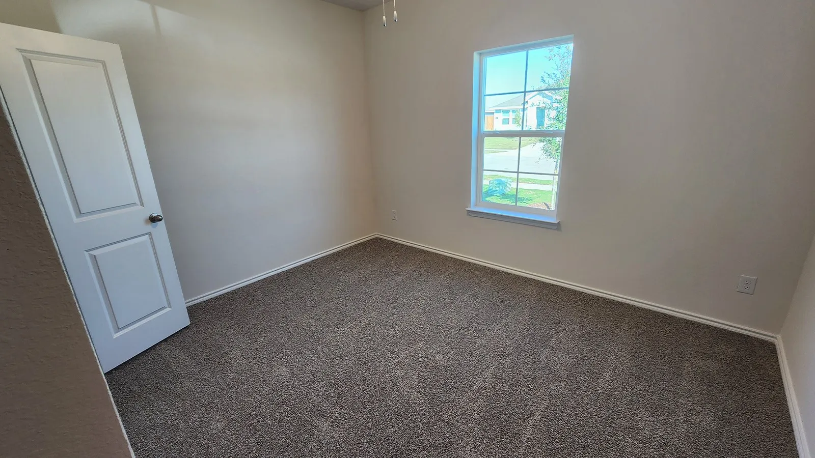 Carpeted room featuring a single window with white trim, a six-panel interior door, and white baseboards