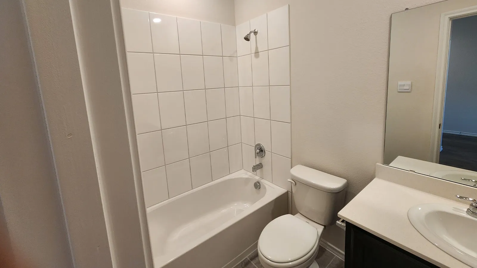 Full bathroom featuring a white tub, chrome shower fixtures, white subway tile surround, and a vanity with an integrated sink and mirror