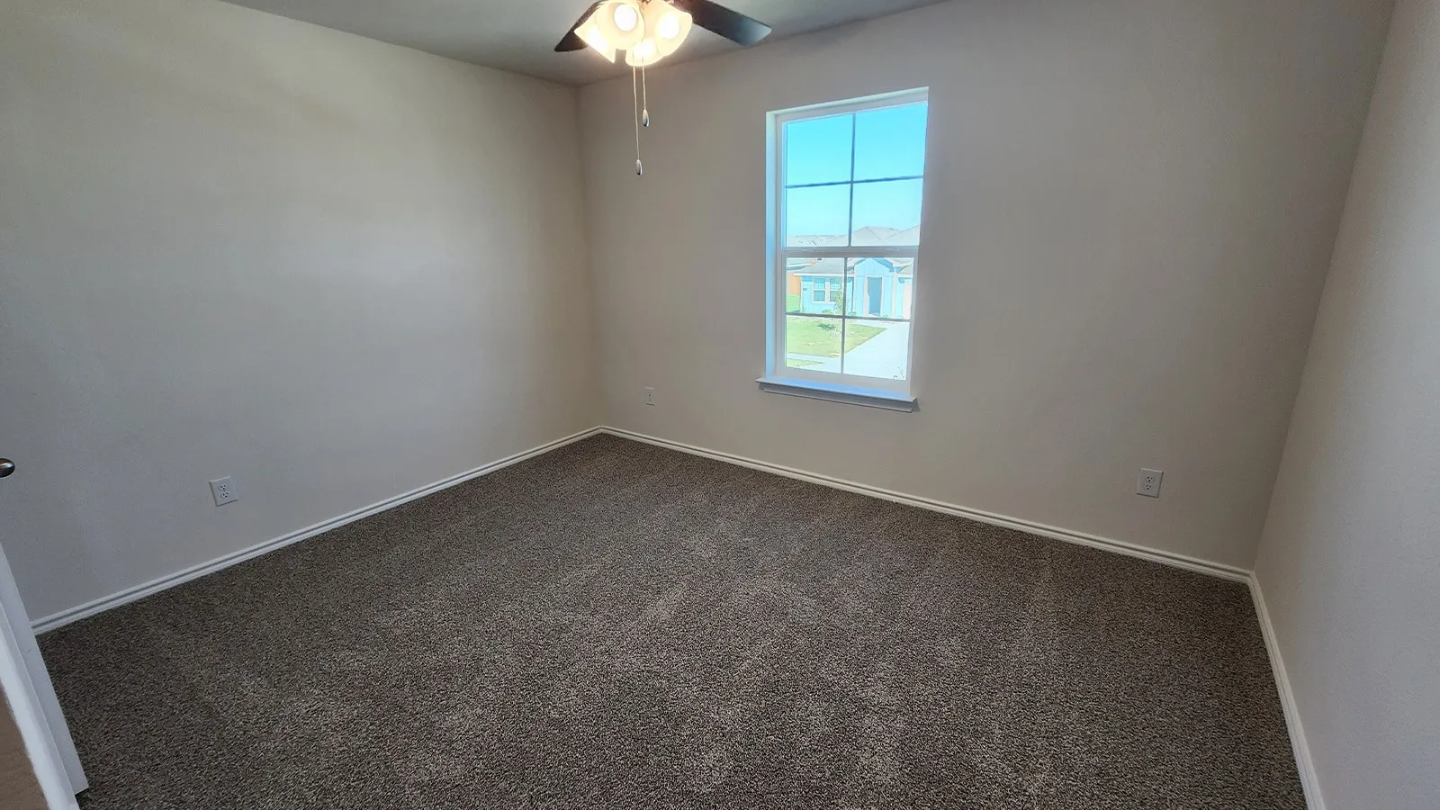 Bedroom featuring textured carpeting, neutral wall paint, and a multi-pane window