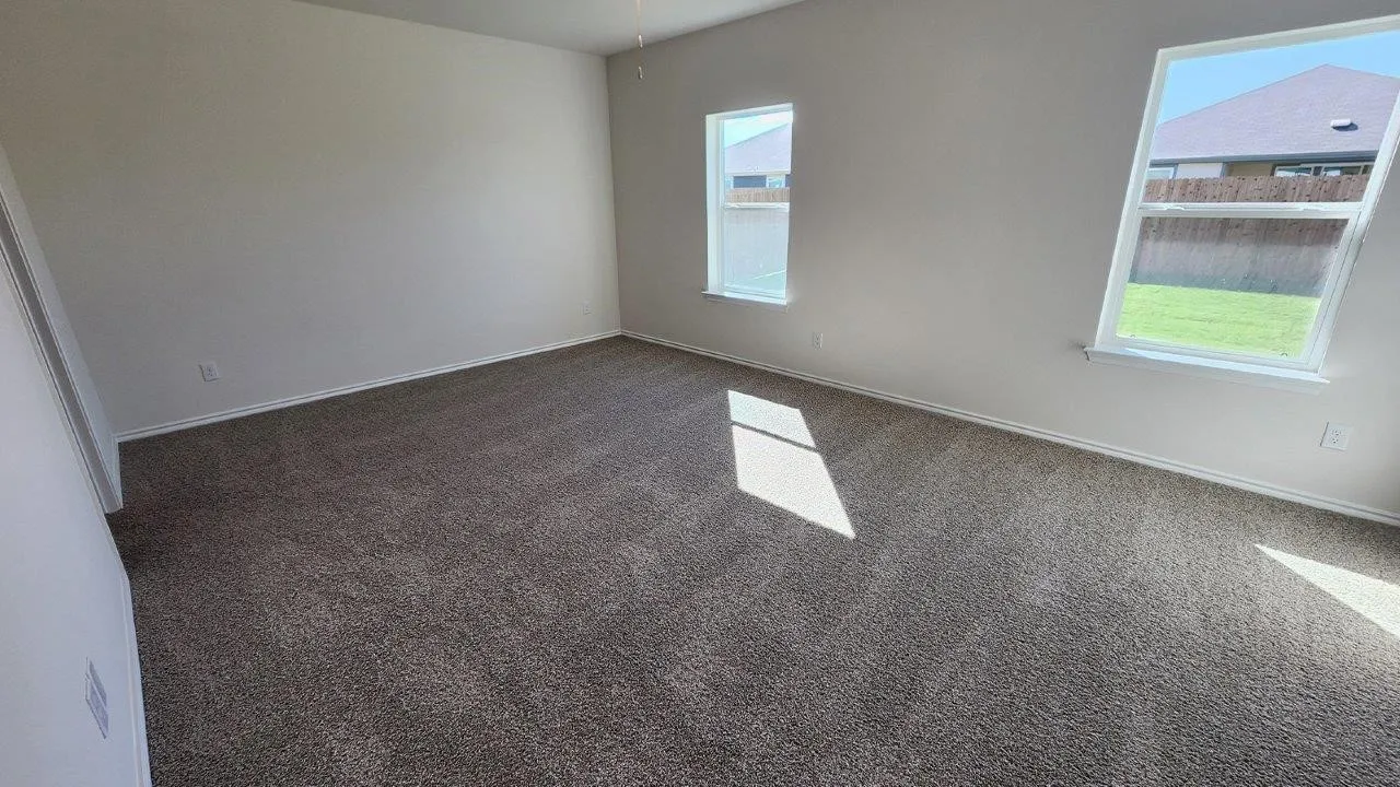 Expansive room with neutral carpeting, white baseboards, and light-toned walls