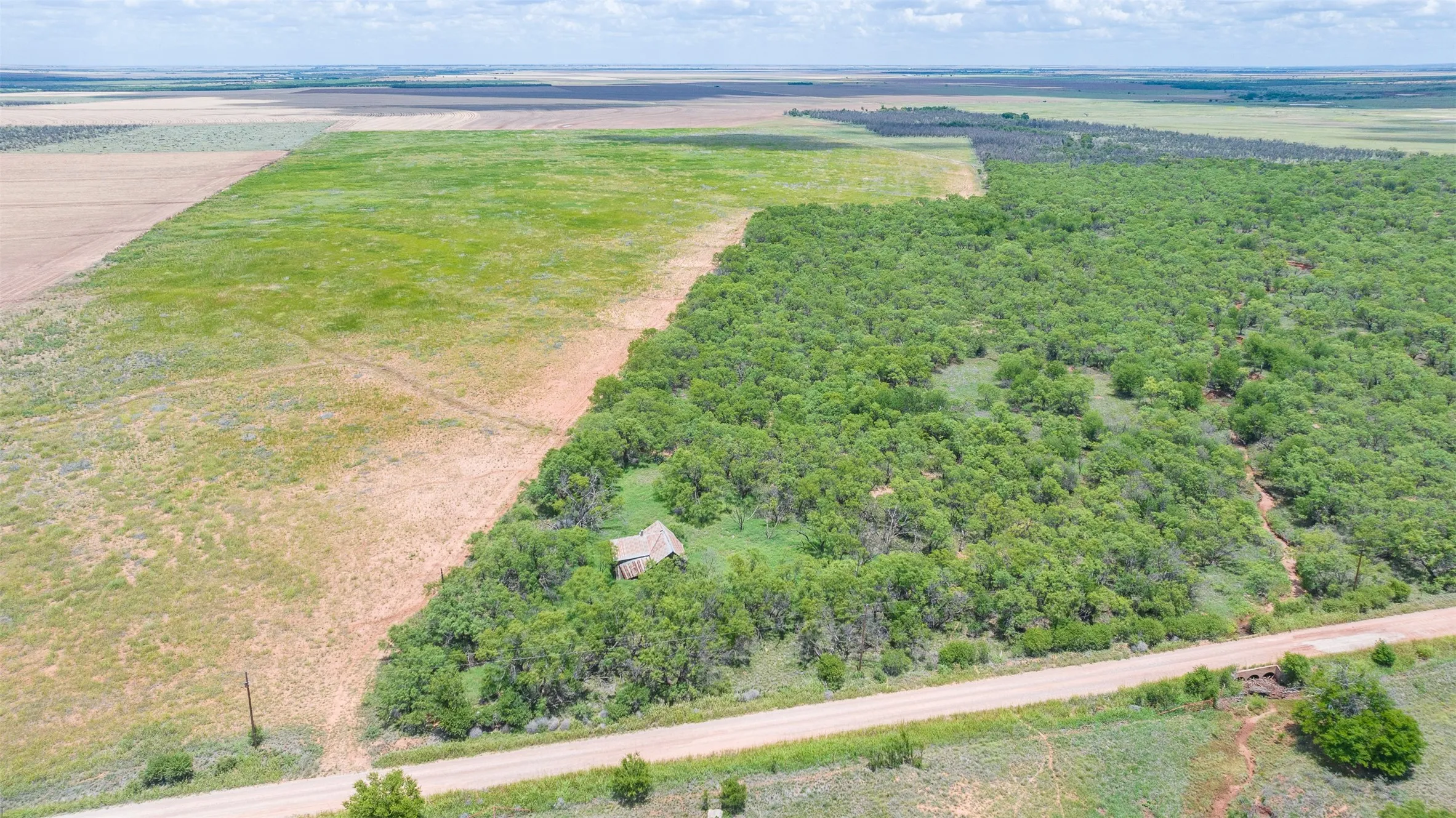 Expansive rural property featuring a mix of open fields and densely wooded areas