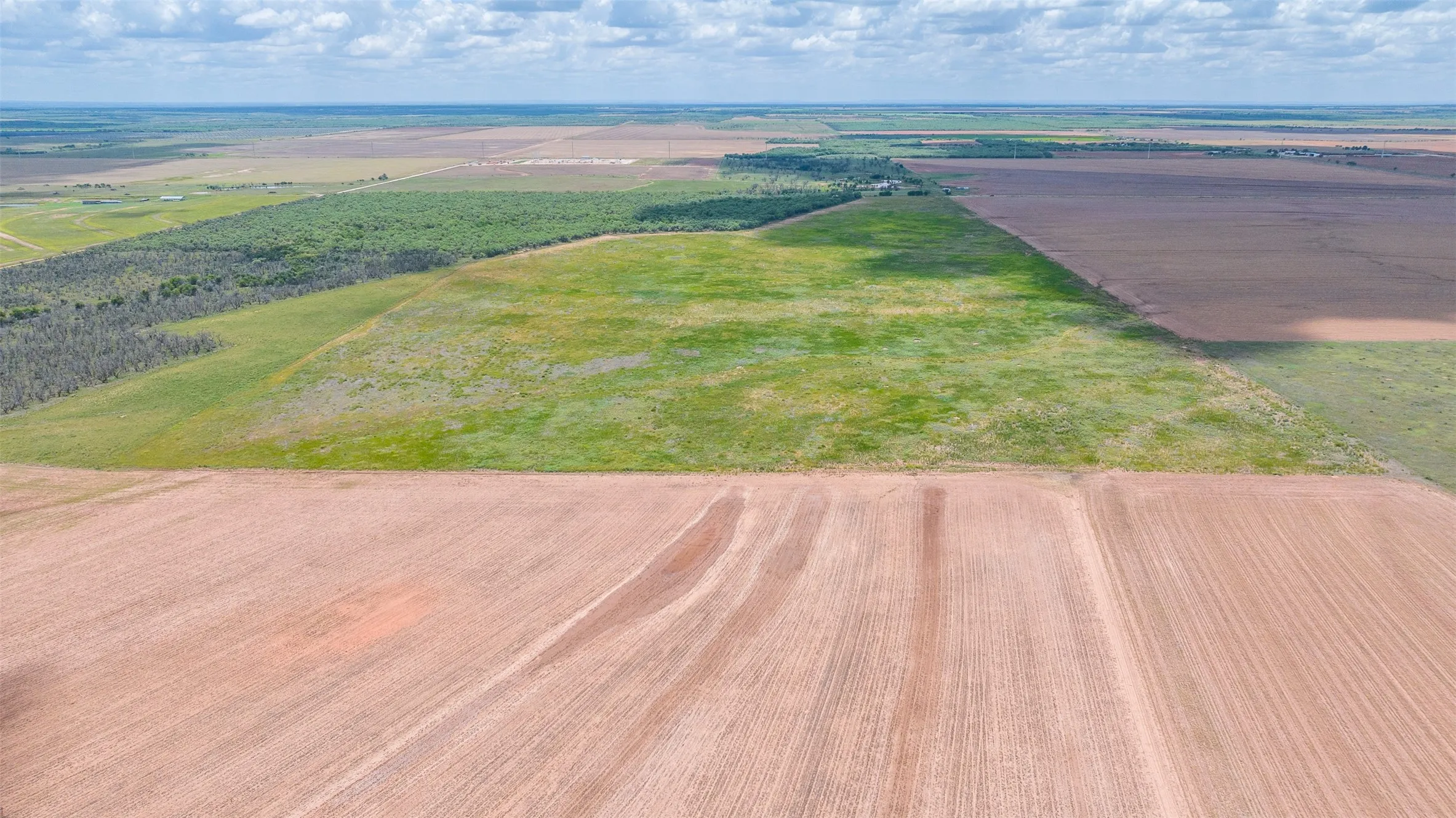 Expansive agricultural land featuring cultivated fields and natural green spaces