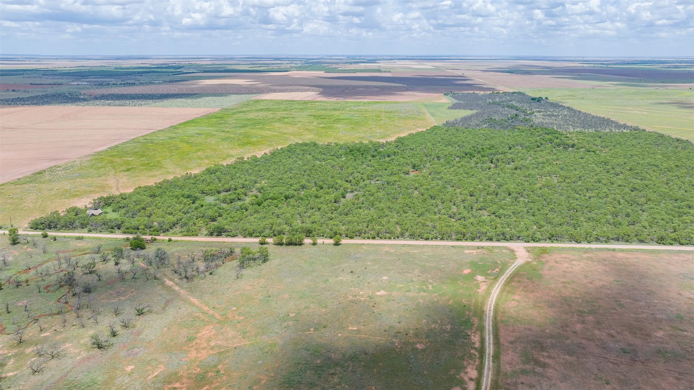 Expansive land parcel featuring a mix of cultivated fields, natural grasslands, and dense tree coverage