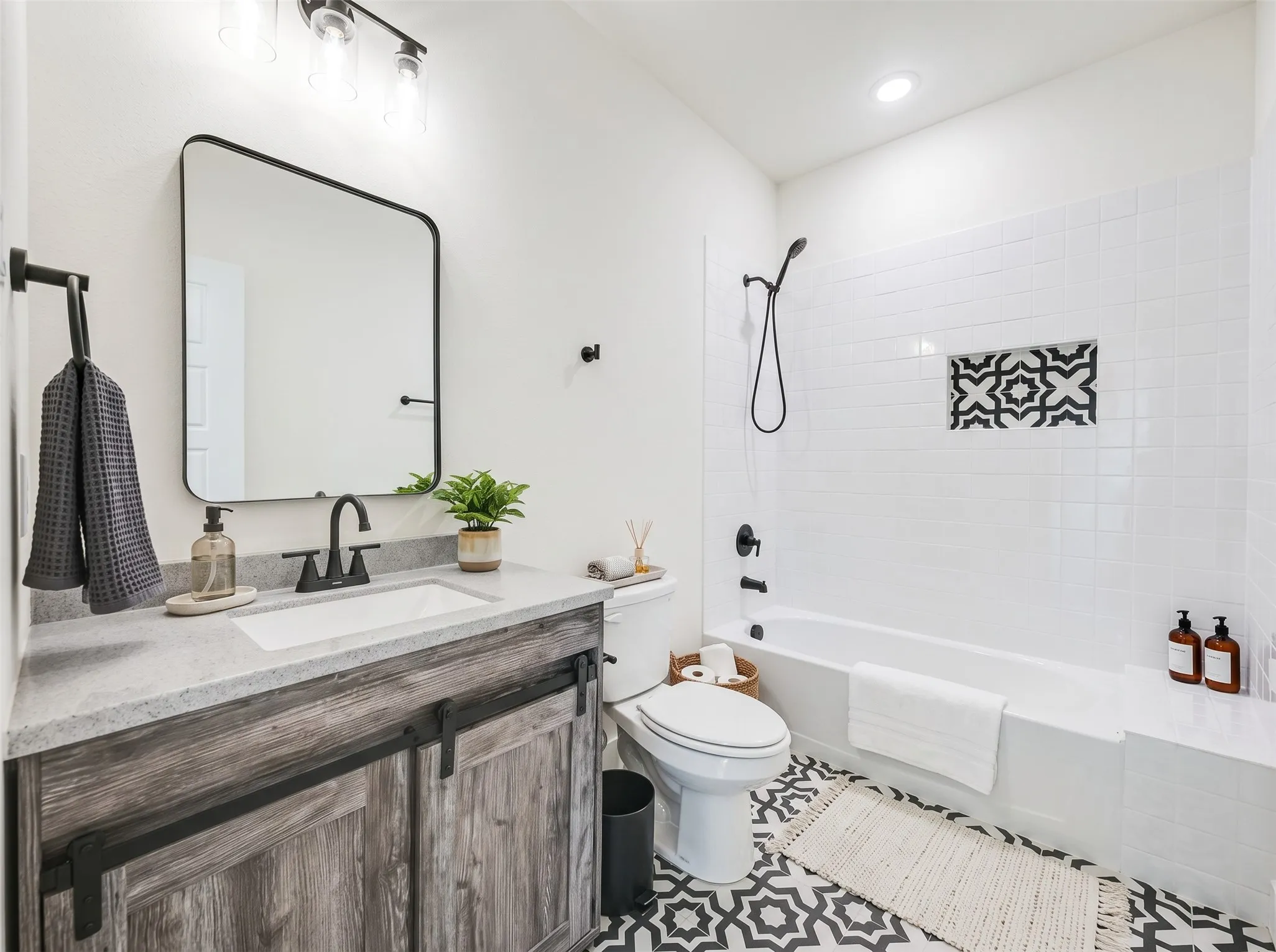 Vanity with a quartz countertop, integrated sink, and wood-finish cabinetry with barn door hardware