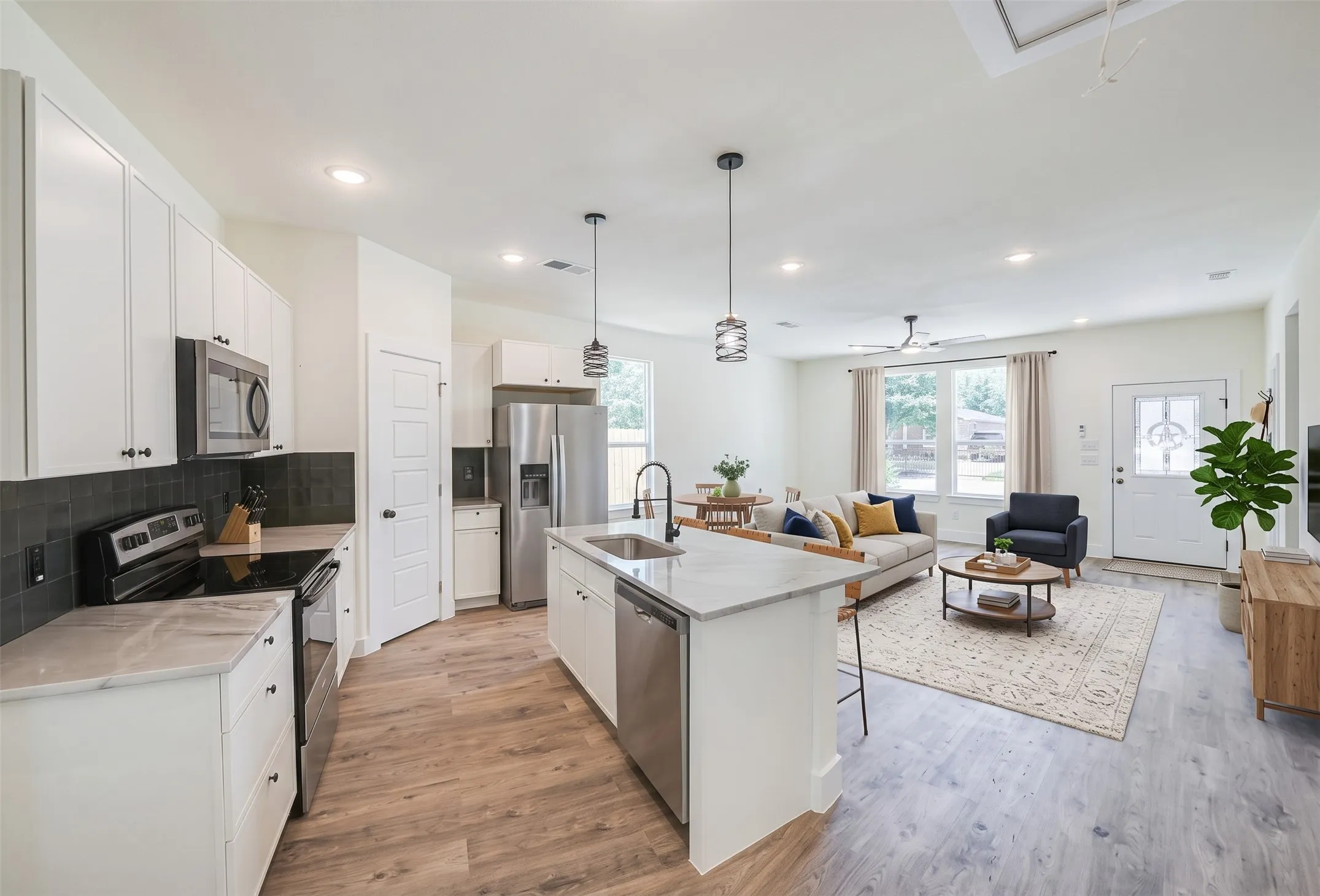 Open-concept living area with wood-finish flooring, recessed lighting, and a ceiling fan