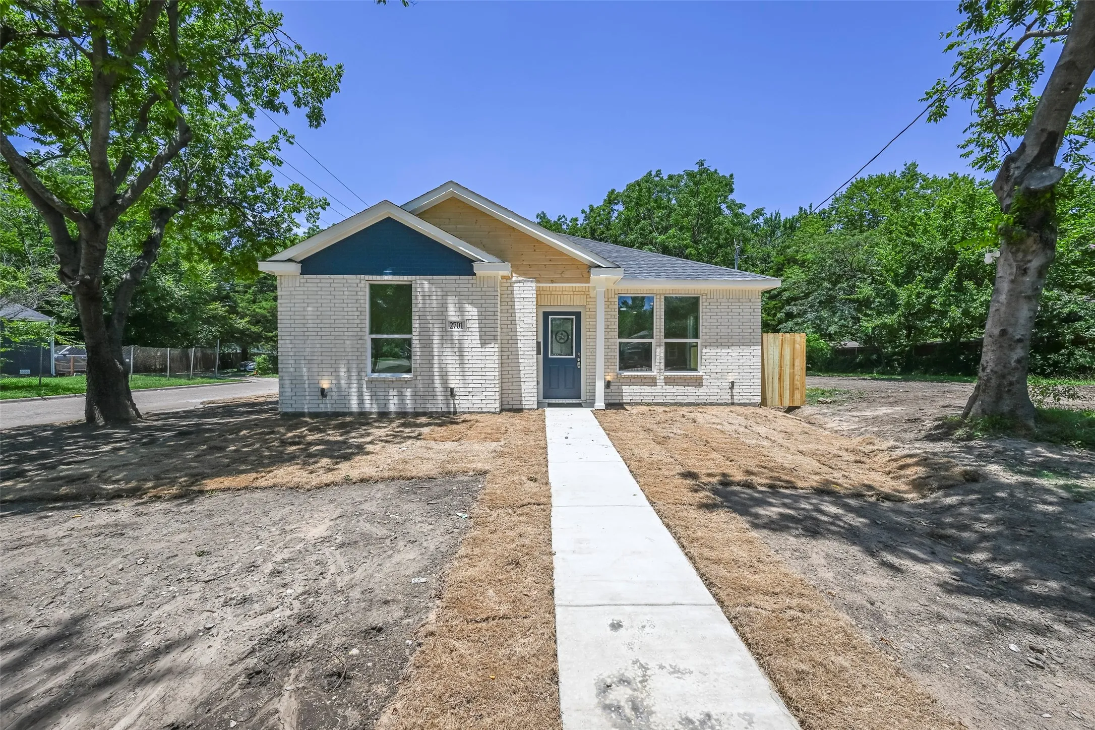 Contemporary exterior featuring white brick siding and a deep blue entry door