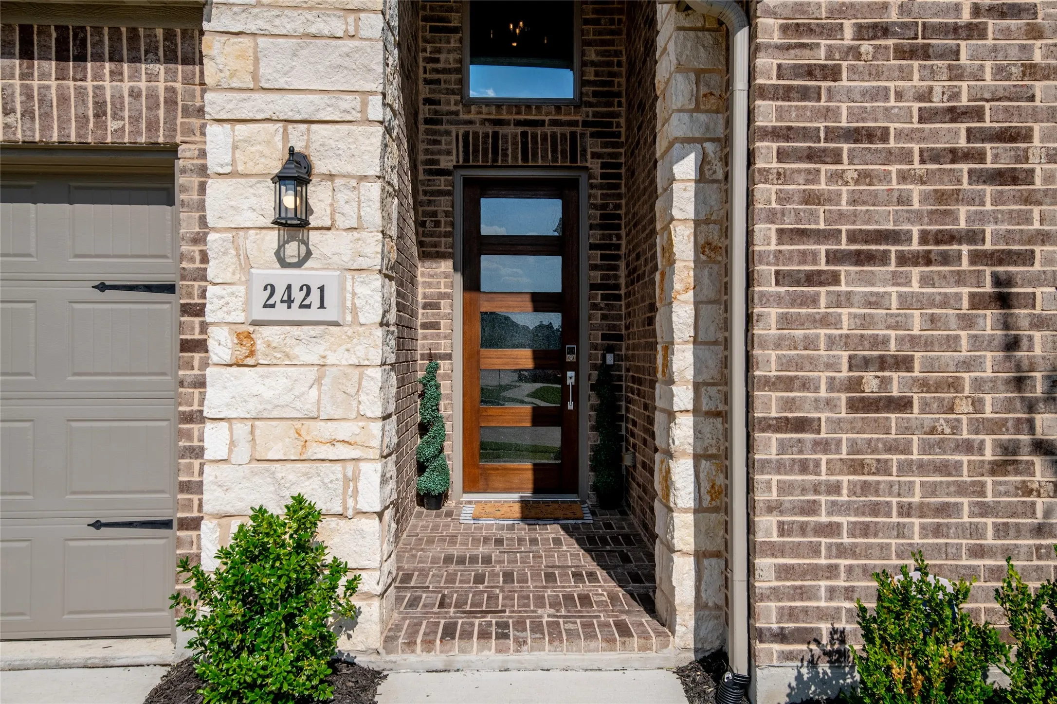 An impressive covered entry and modern glass-panel front door create a warm welcome, setting the stage for the luxury and thoughtful design found throughout this exceptional home.