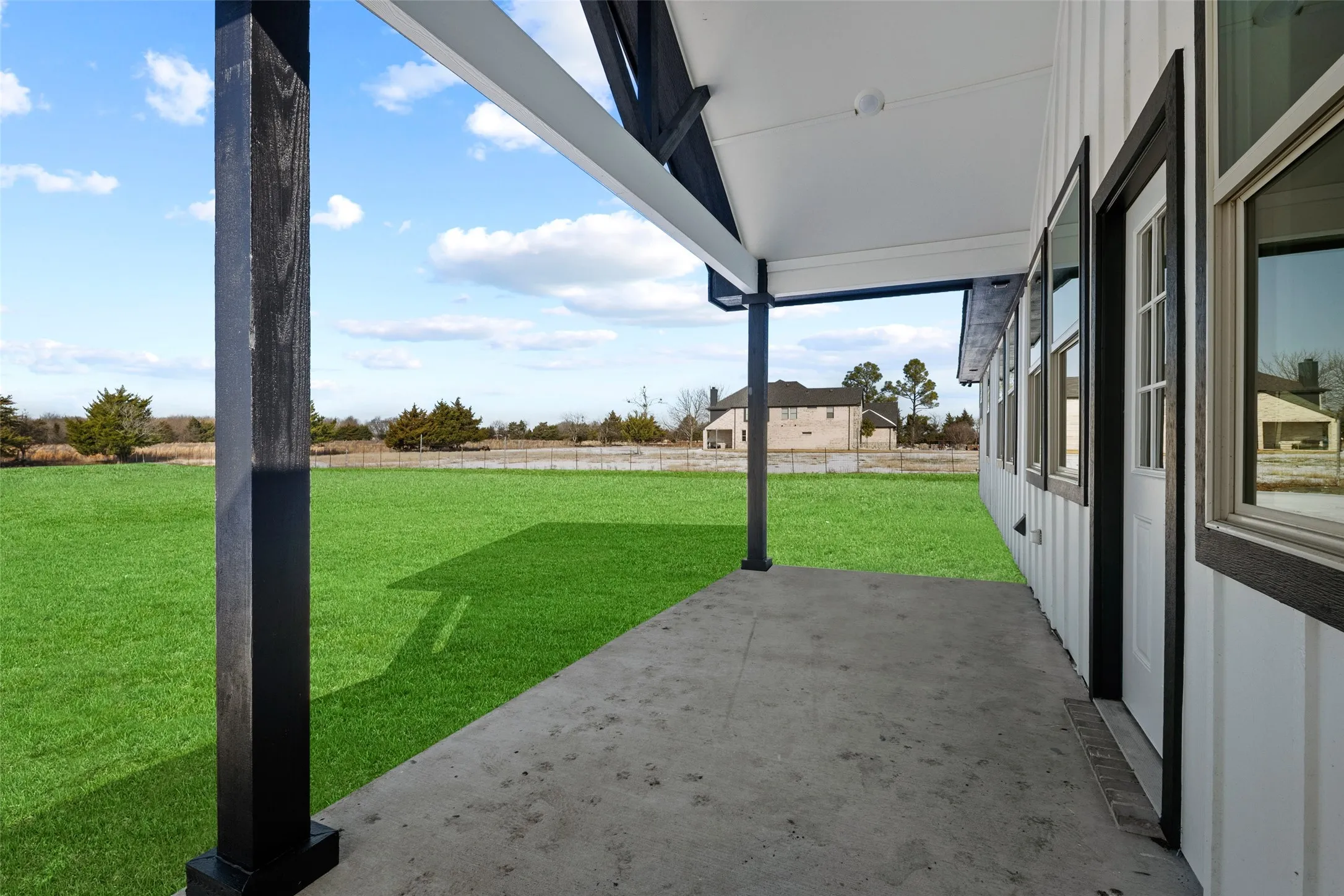 Expansive concrete patio with a white ceiling and dark wood-finish support beams