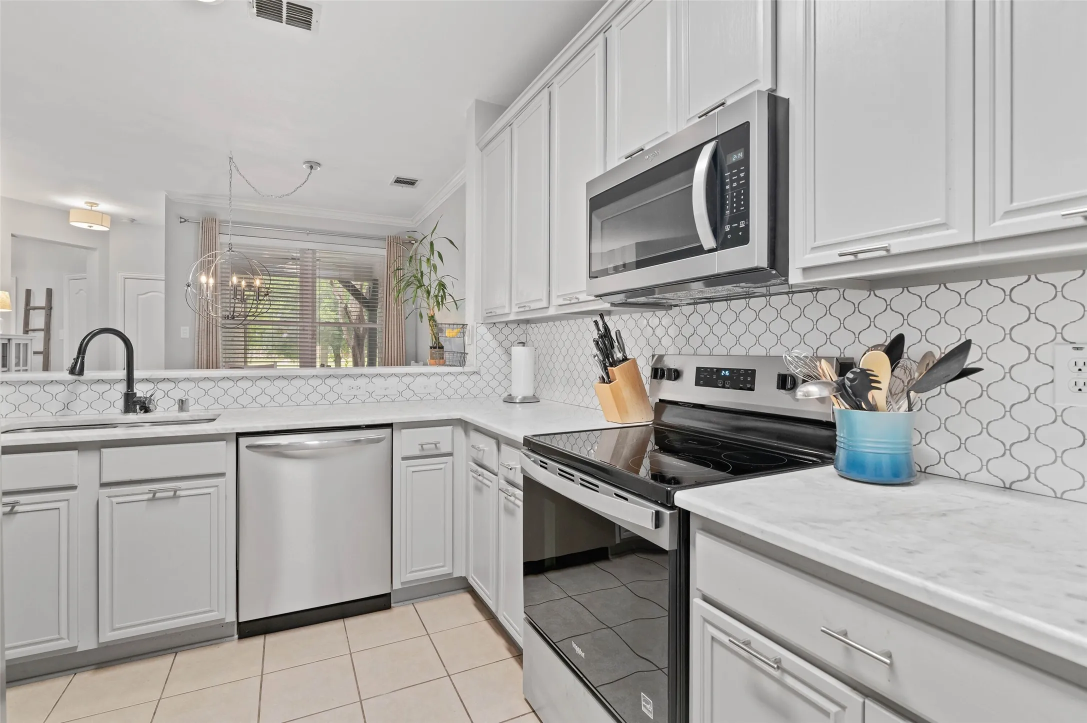 Kitchen featuring light-finish cabinetry, stainless steel appliances, a patterned tile backsplash, and light countertops