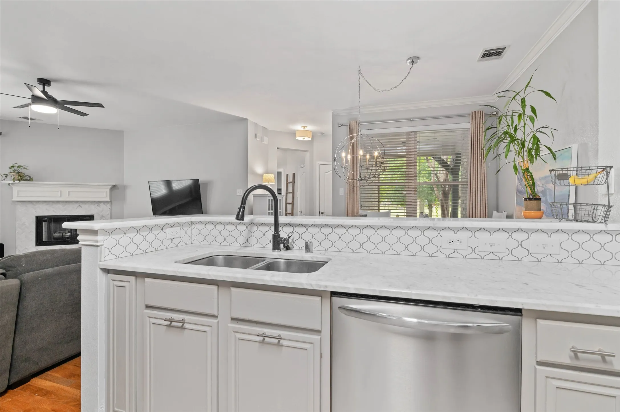 Kitchen peninsula featuring light-toned cabinetry, a stainless steel double basin sink with a dark-toned faucet, and a stainless steel dishwasher