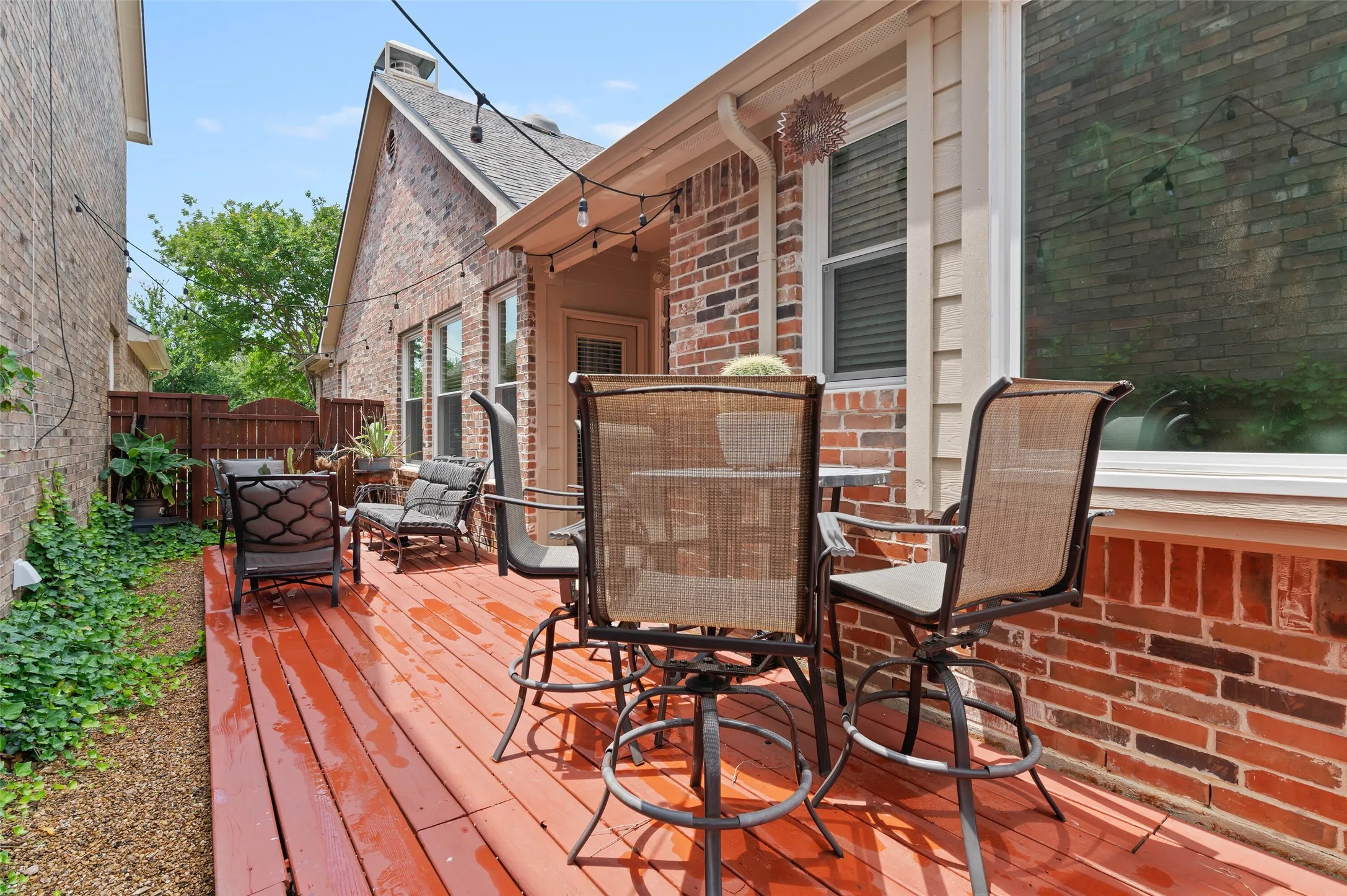 Red-stained wood deck featuring string lighting