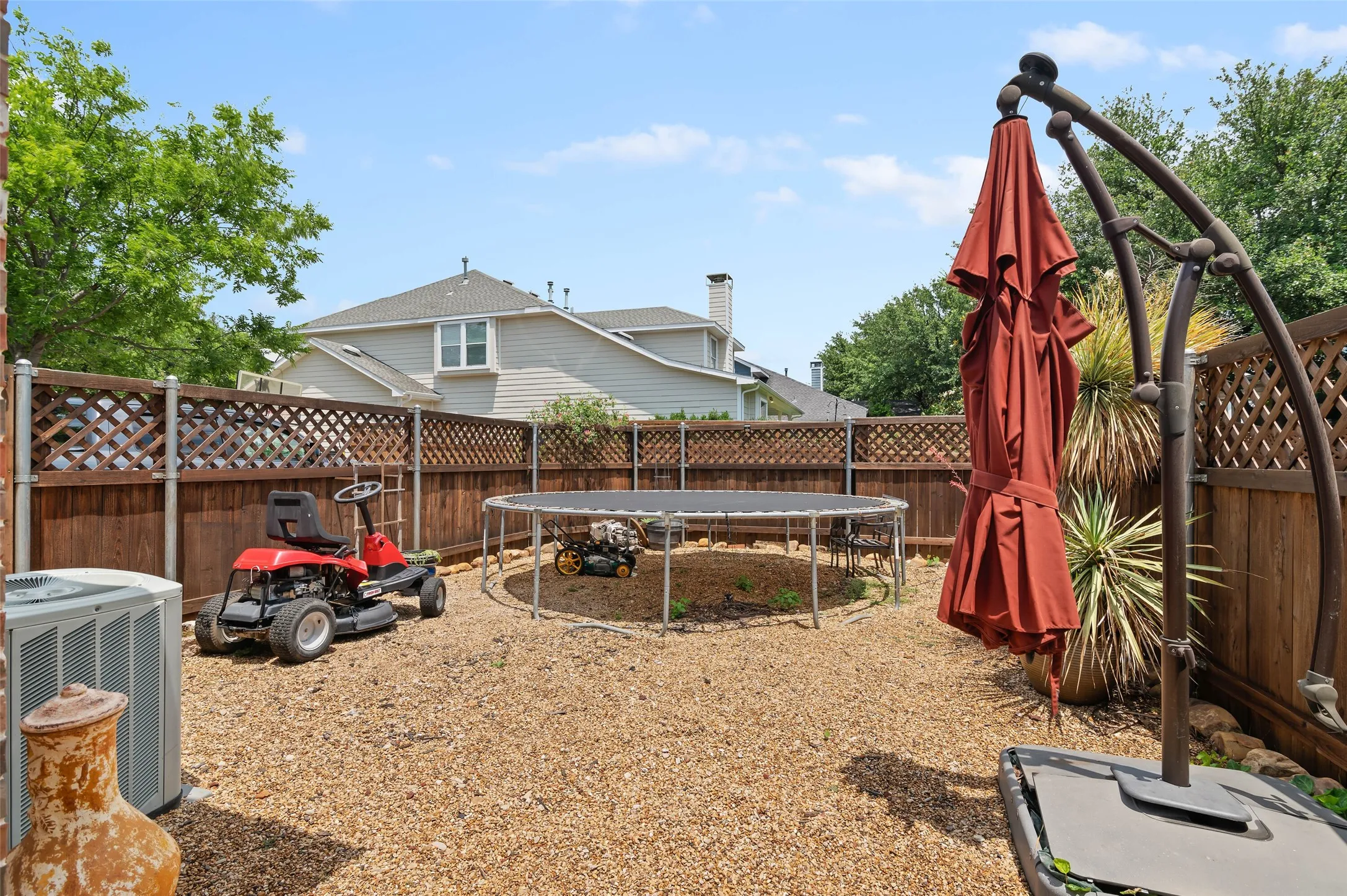 Enclosed backyard featuring wood fencing with lattice accents and a gravel surface
