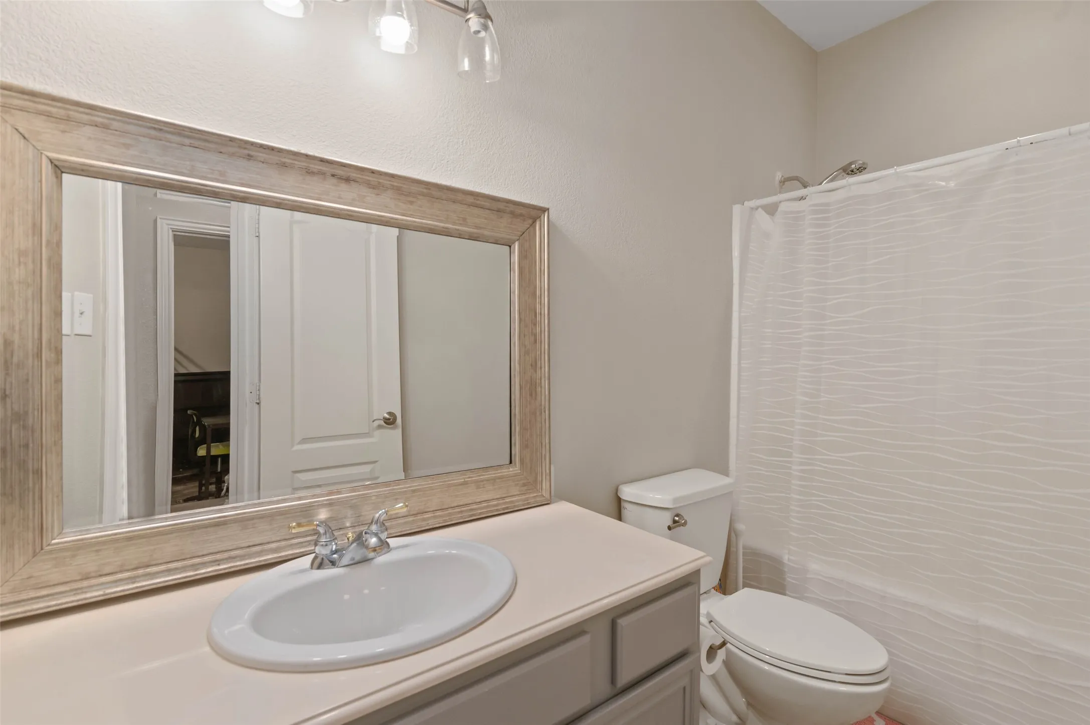 Bathroom with a single vanity, large framed mirror, and a shower-tub combination