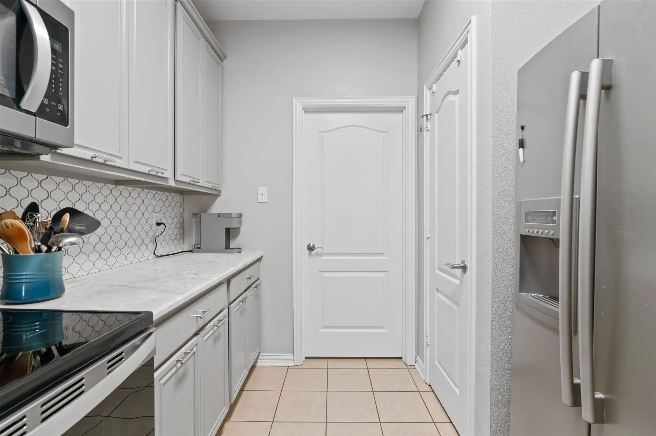 Kitchen featuring light cabinetry, a patterned tile backsplash, and light-toned countertops