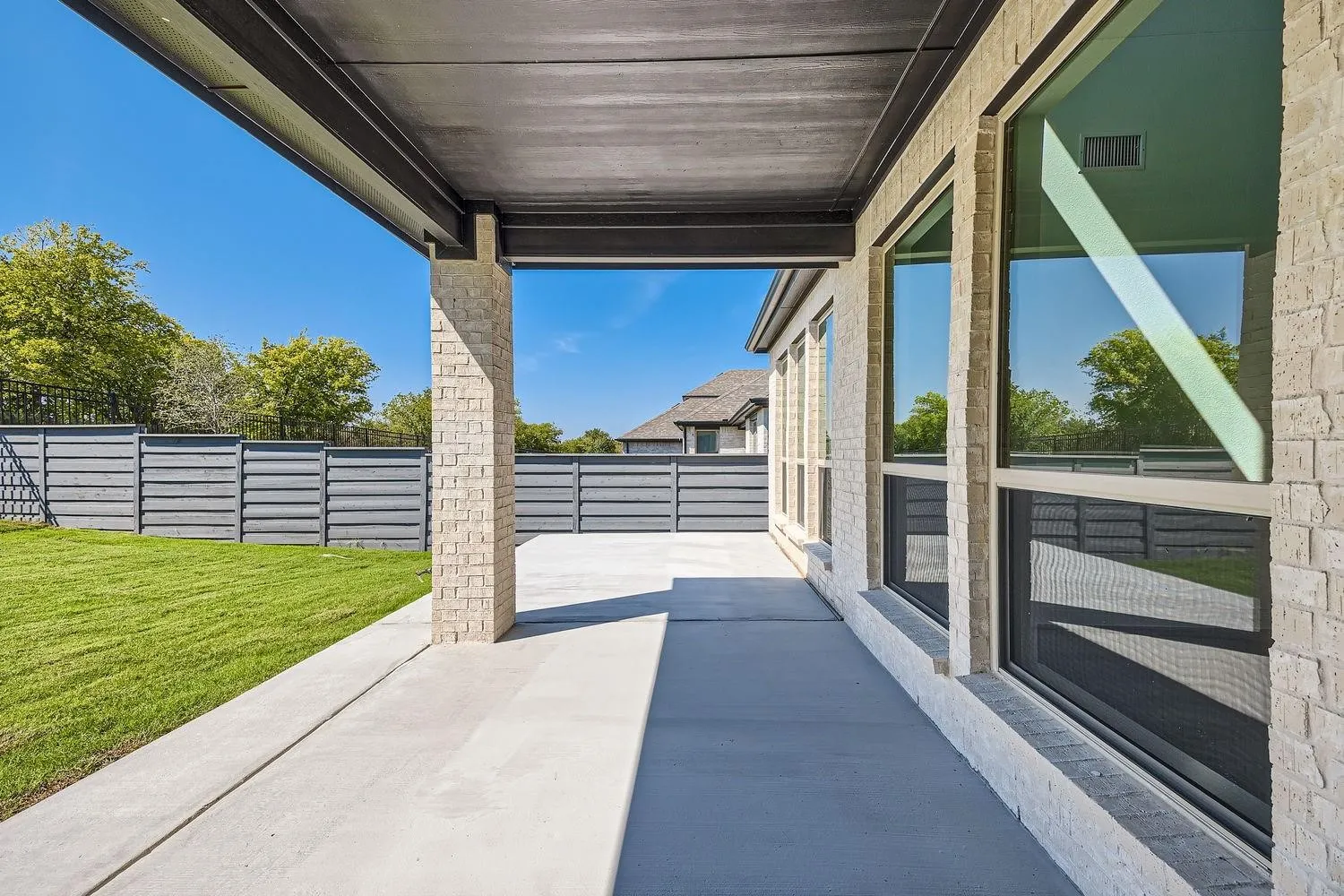 Expansive covered patio featuring a concrete surface and a light brick column