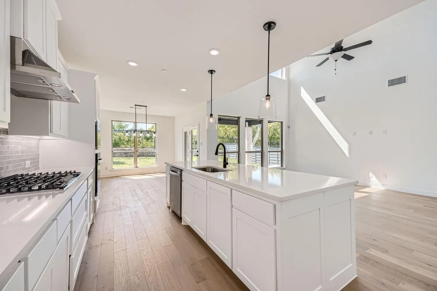 Modern kitchen featuring white shaker cabinetry, stainless steel appliances, a center island with sink, and light wood-finish flooring