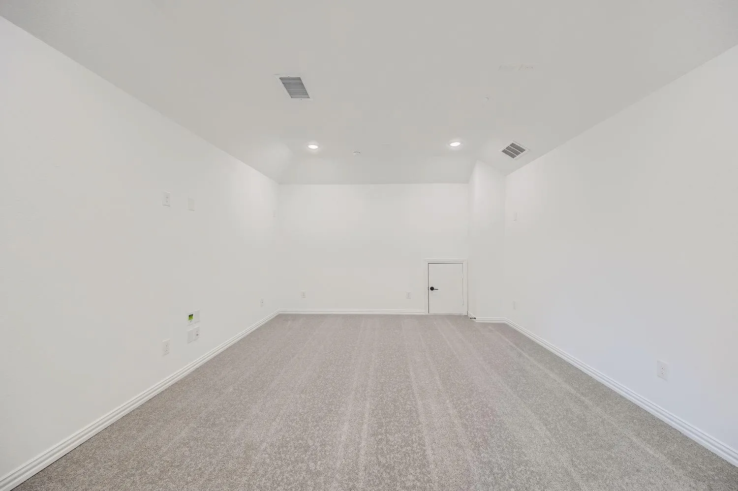 Spacious room featuring neutral carpeting, white painted walls, recessed lighting, and a white baseboard trim