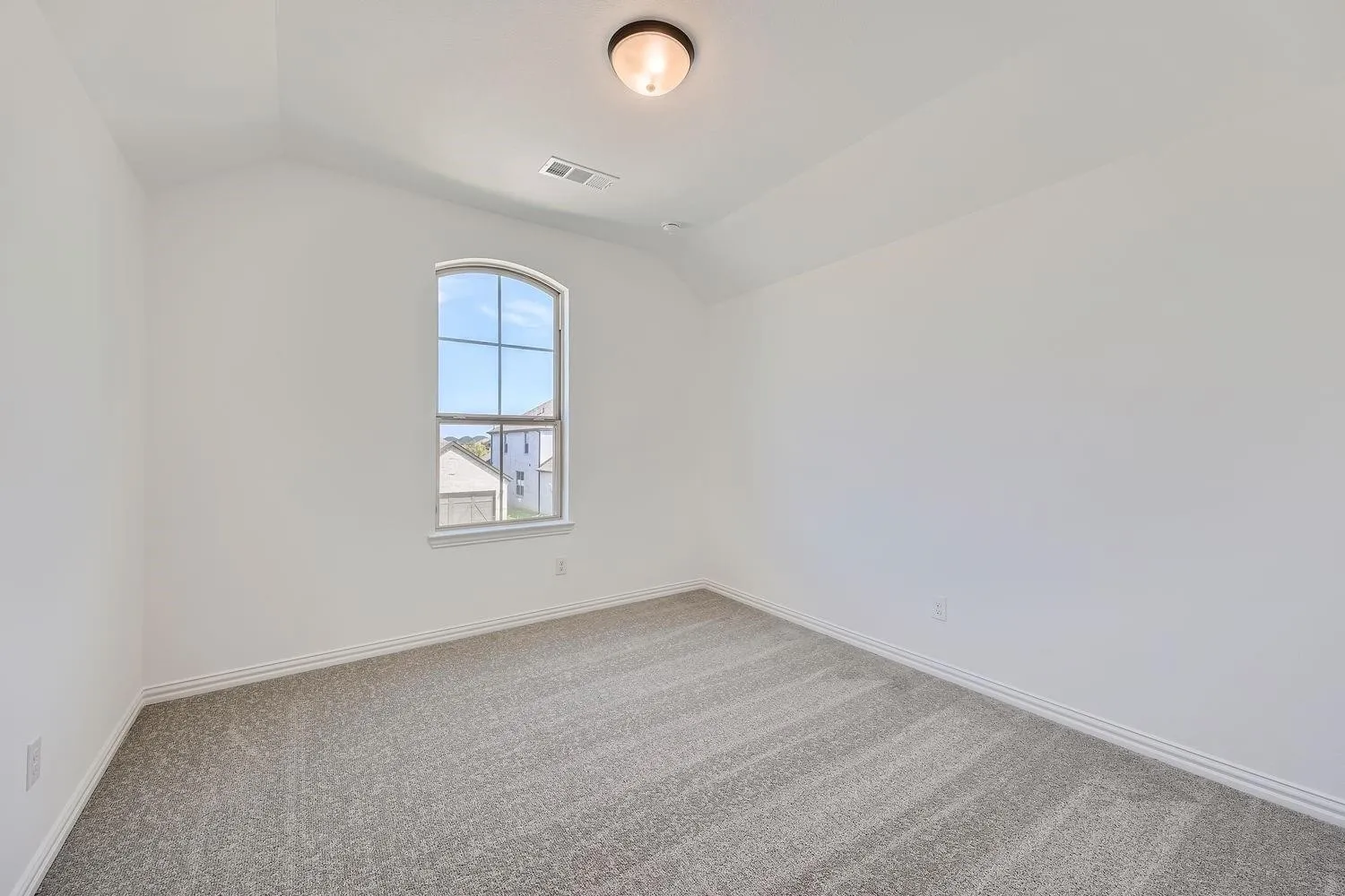 Carpeted room featuring a vaulted ceiling, an arched window, and white trim