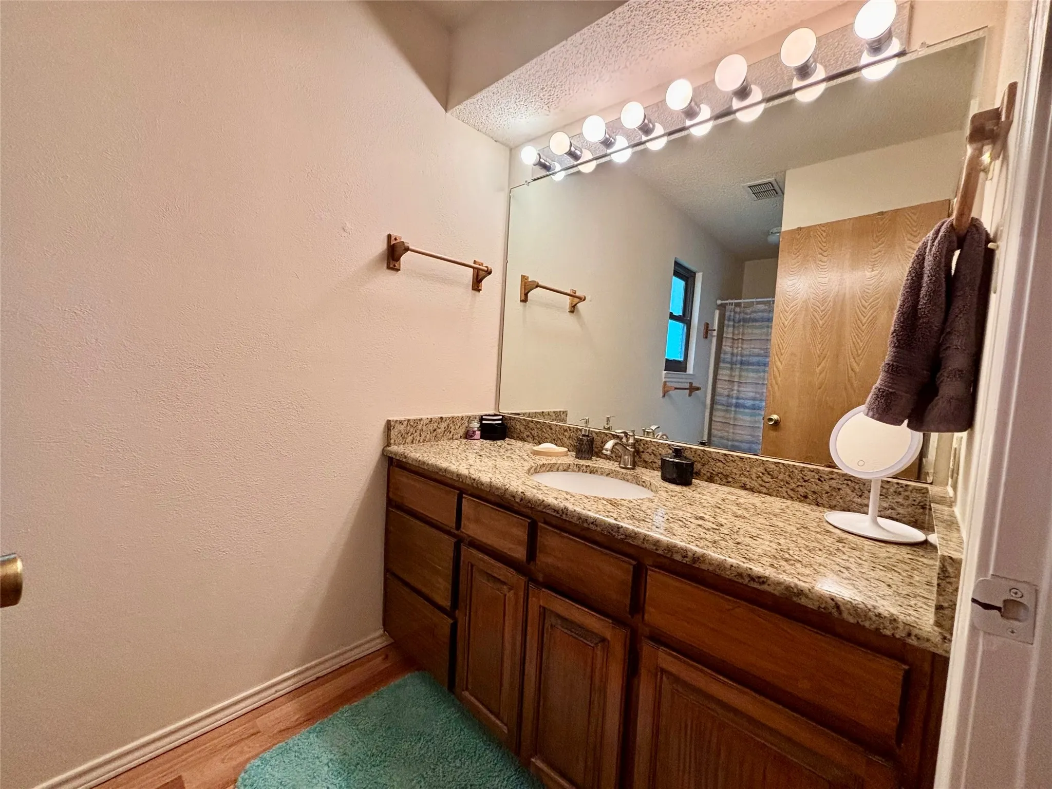 Single vanity with a granite countertop, undermount sink, and wood-finish cabinetry