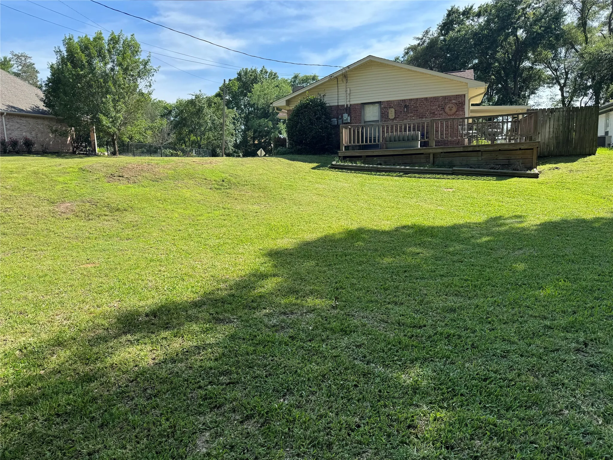 Spacious backyard featuring an elevated wood deck and a partial wood privacy fence