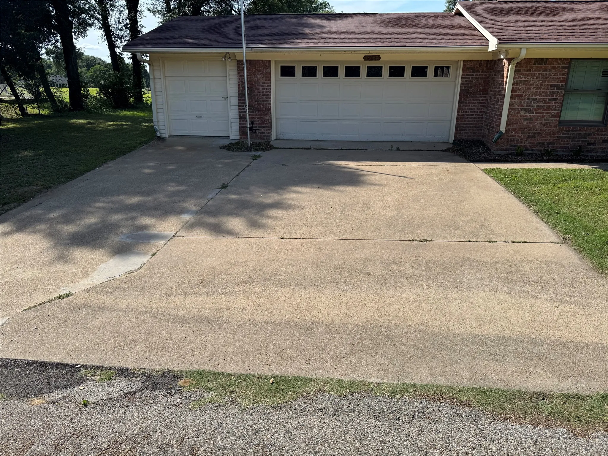 Concrete driveway with an attached two-car garage and an additional single-car pull thru golf cart garage.