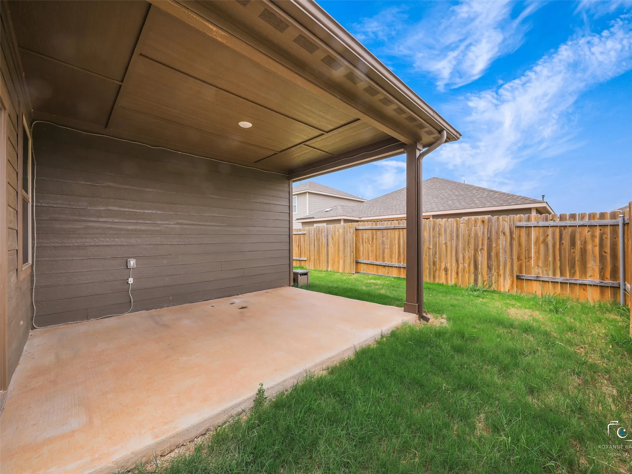 Covered patio with concrete flooring, recessed lighting, wood-finish siding, and a wooden privacy fence
