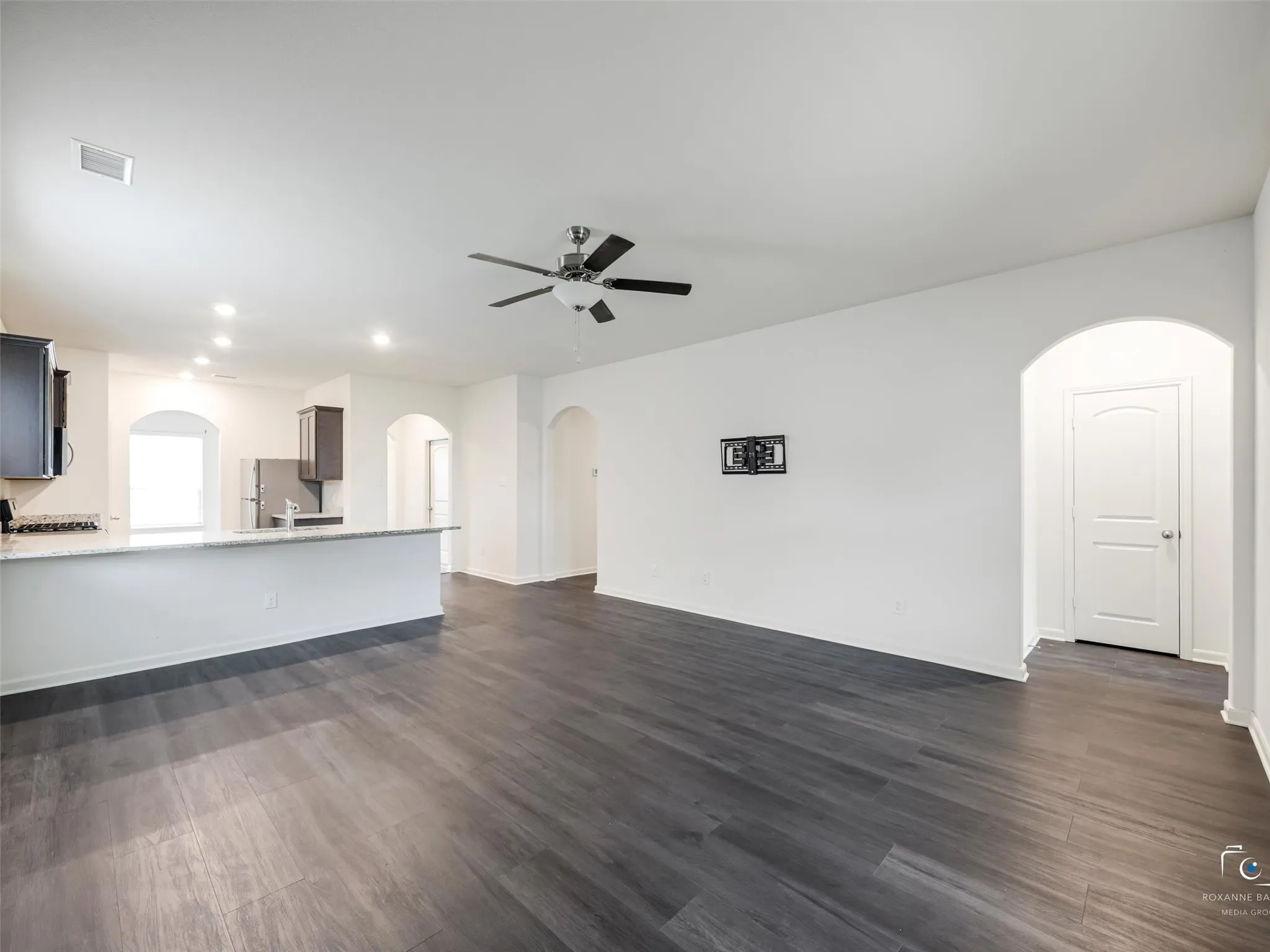Expansive living area featuring wood-finish flooring, a ceiling fan, and recessed lighting