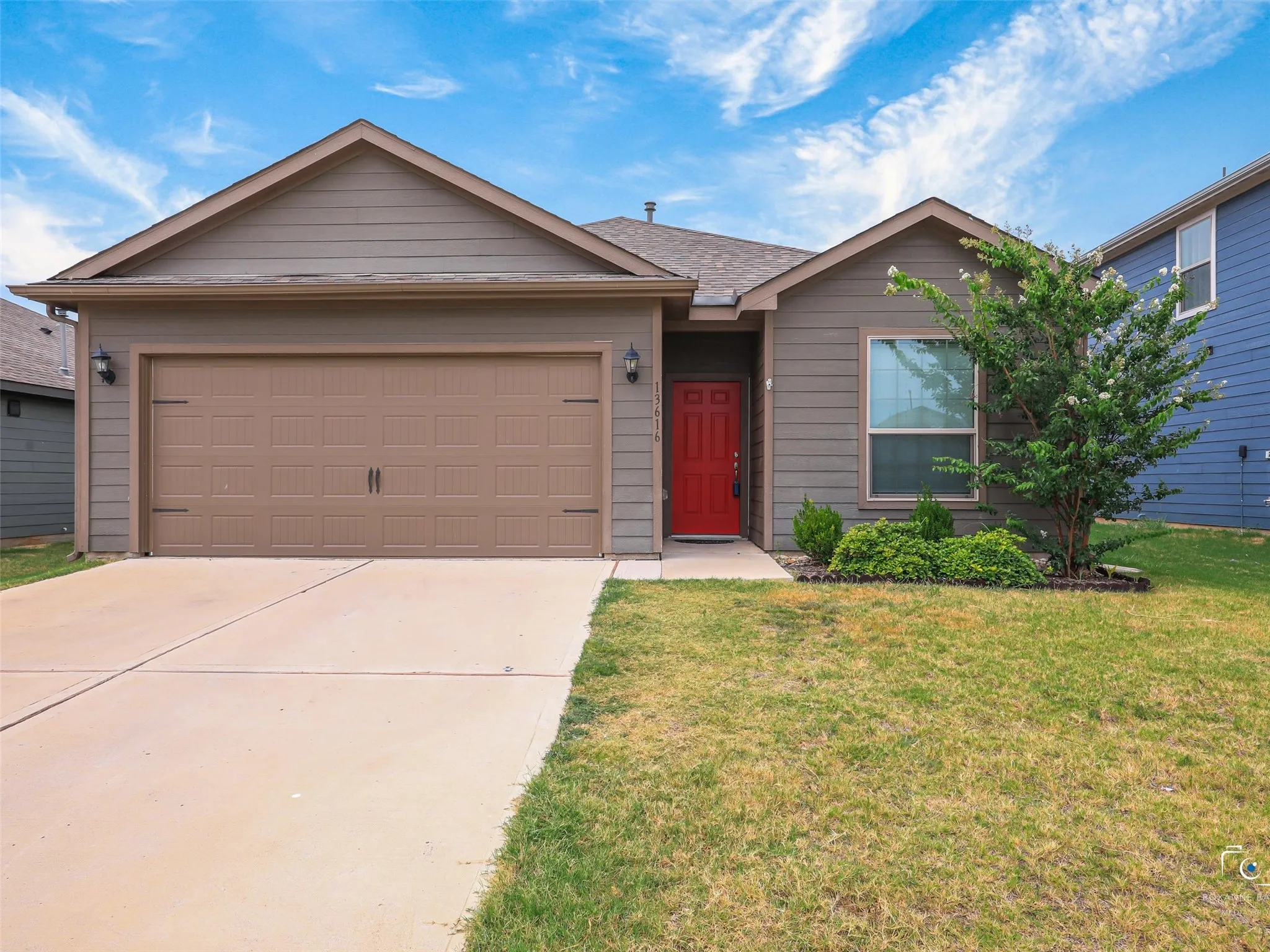 Contemporary exterior with horizontal siding, an attached two-car garage, a vibrant red entry door, and a concrete driveway