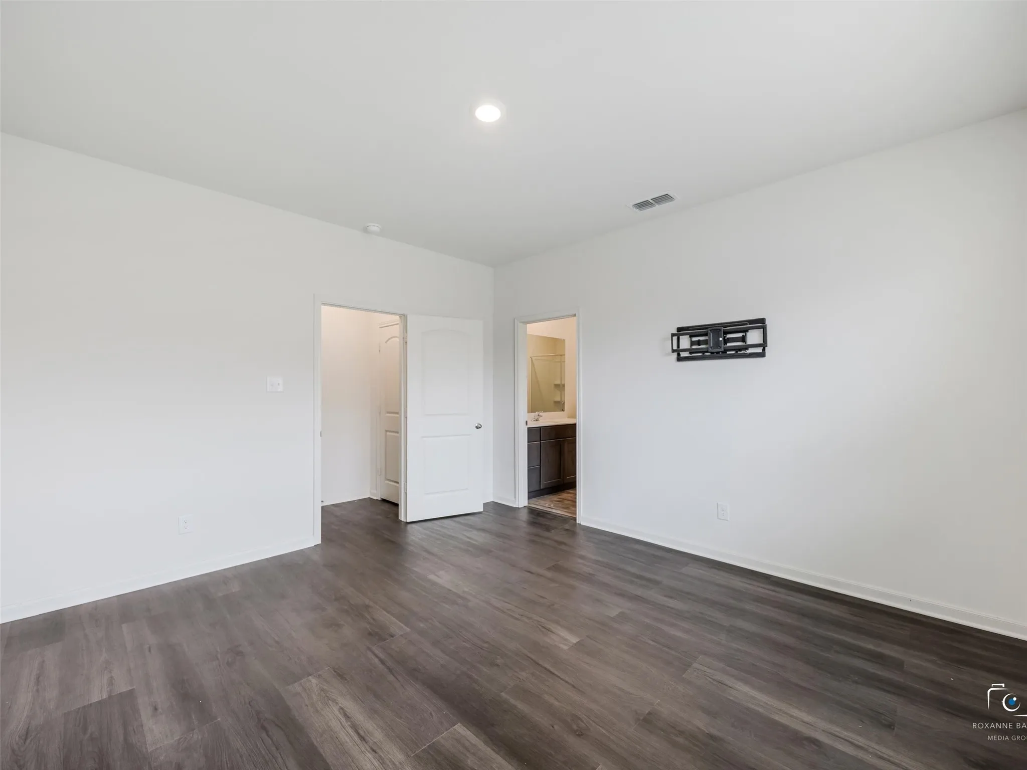 Recessed ceiling lighting, wood-finish flooring, white painted walls, and a wall-mounted television bracket