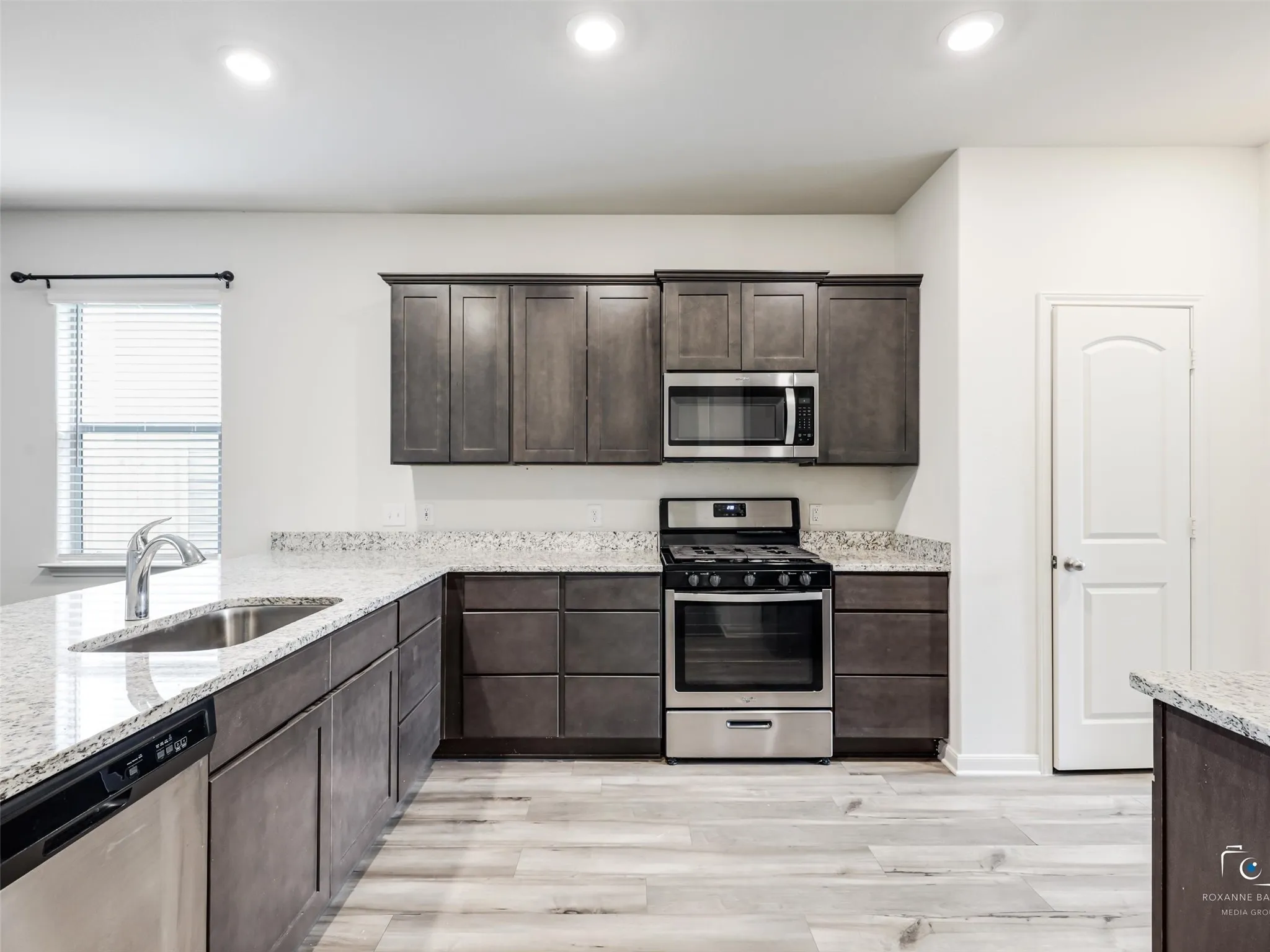 Kitchen featuring wood-finish cabinetry, stainless steel appliances, speckled countertops, and a stainless steel sink with a gooseneck faucet