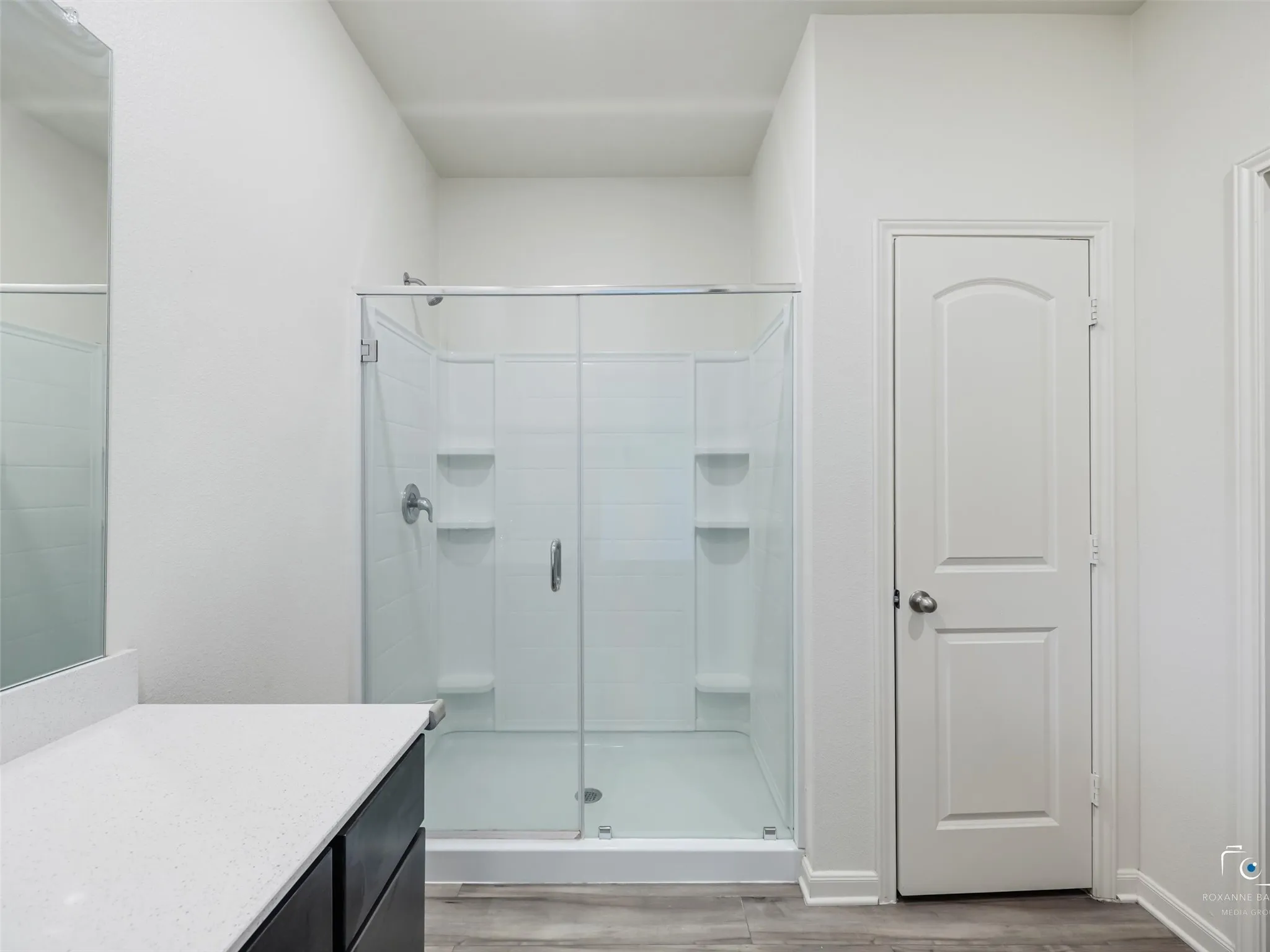 Spacious walk-in shower with clear glass enclosure and built-in shelving
