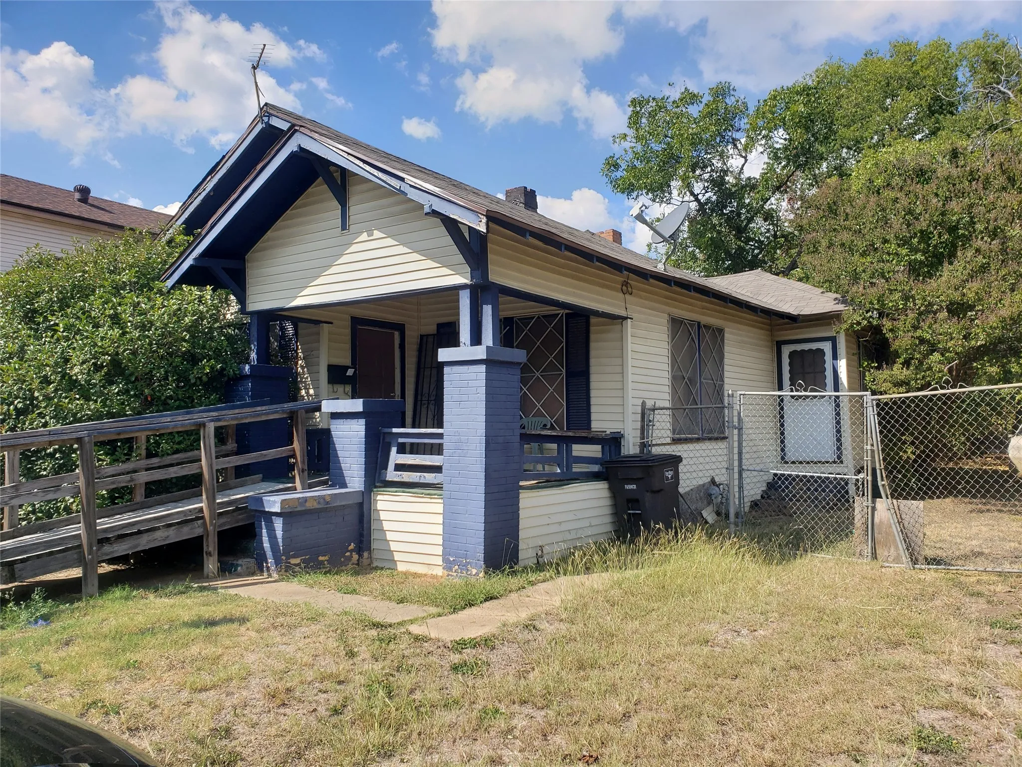 Bungalow-style home with covered porch, a chimney, and a gate