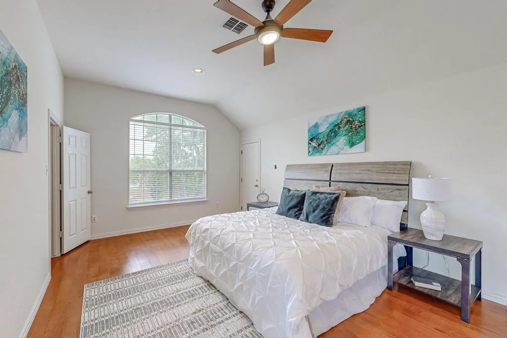 Bedroom with wood-finish flooring, a vaulted ceiling, and an arched window