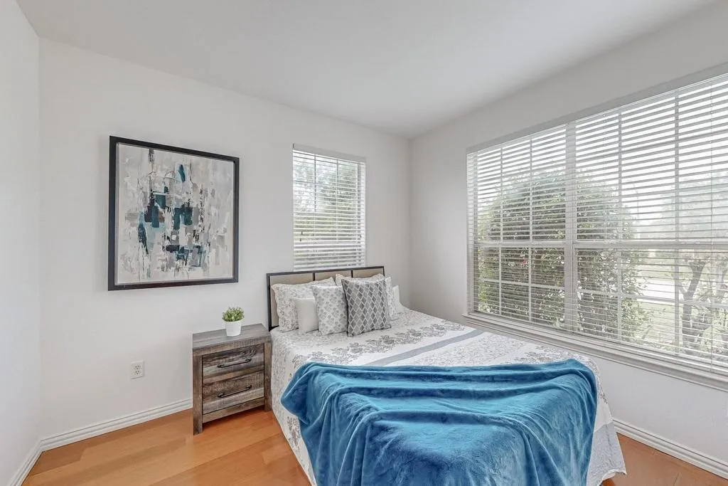 Room featuring two windows with white blinds, light wood-finish flooring, and white baseboards