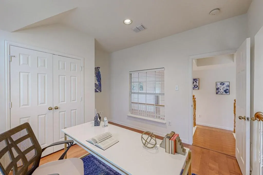 Room featuring light wood-finish flooring, white walls, and a window with blinds