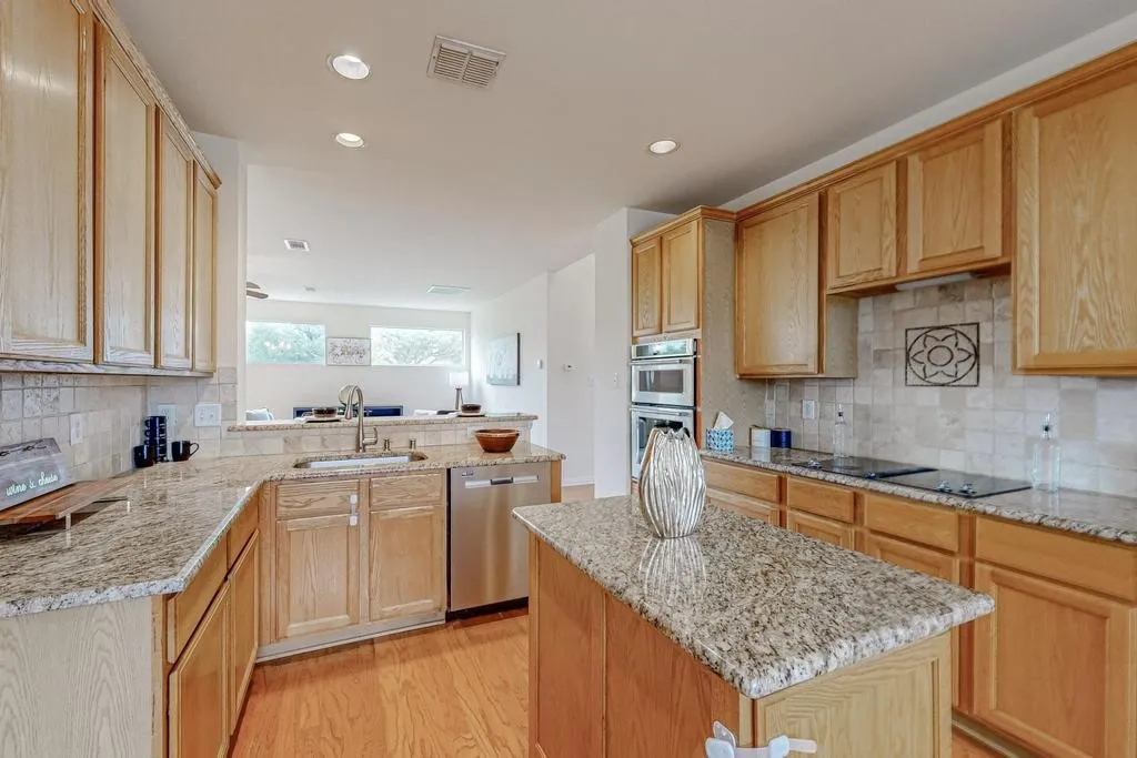 Kitchen featuring wood-finish cabinetry, granite countertops, and a tiled backsplash