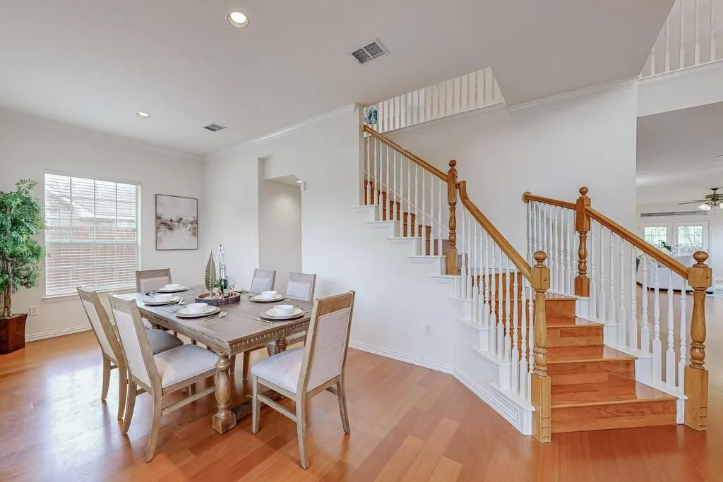 Hardwood flooring extending throughout, featuring a staircase with wood newel posts and handrails, white risers, and white balusters