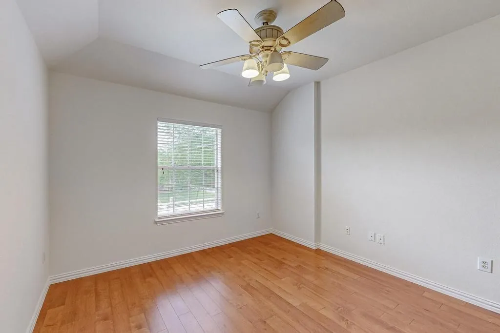 Room featuring wood-finish flooring, white walls, and a ceiling fan with integrated lighting
