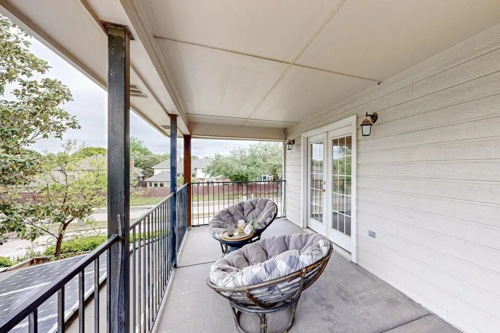 Covered balcony featuring concrete flooring and a black metal railing
