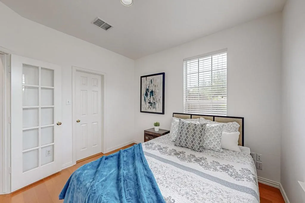 Room featuring wood-finish flooring, a window with blinds, and white walls