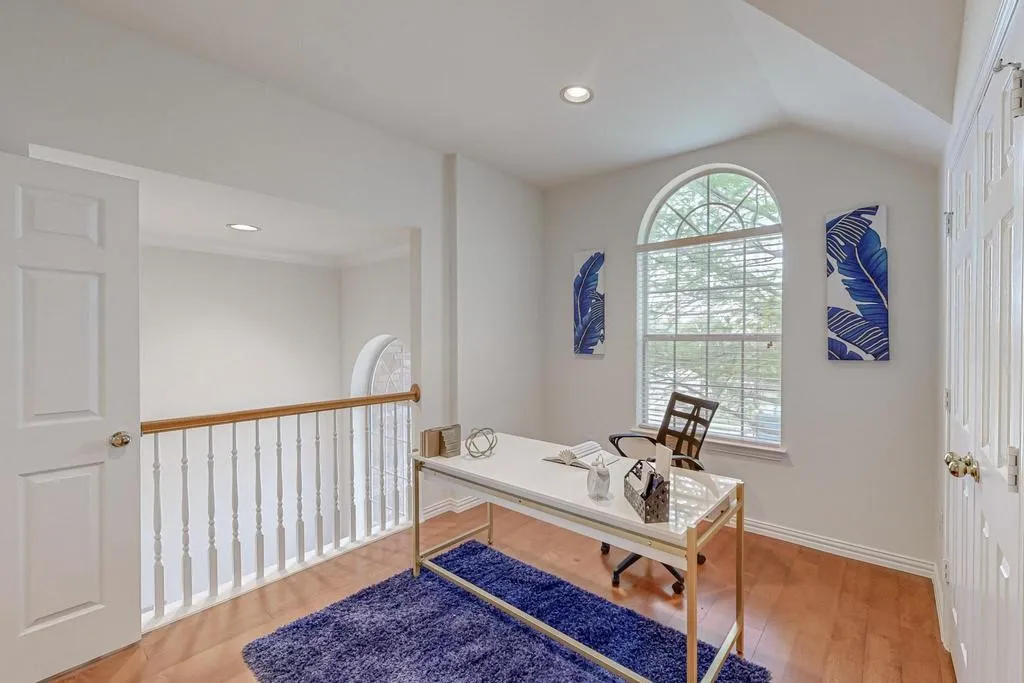 Loft space featuring wood-finish flooring, an arched window, white walls, recessed lighting, and a white paneled door