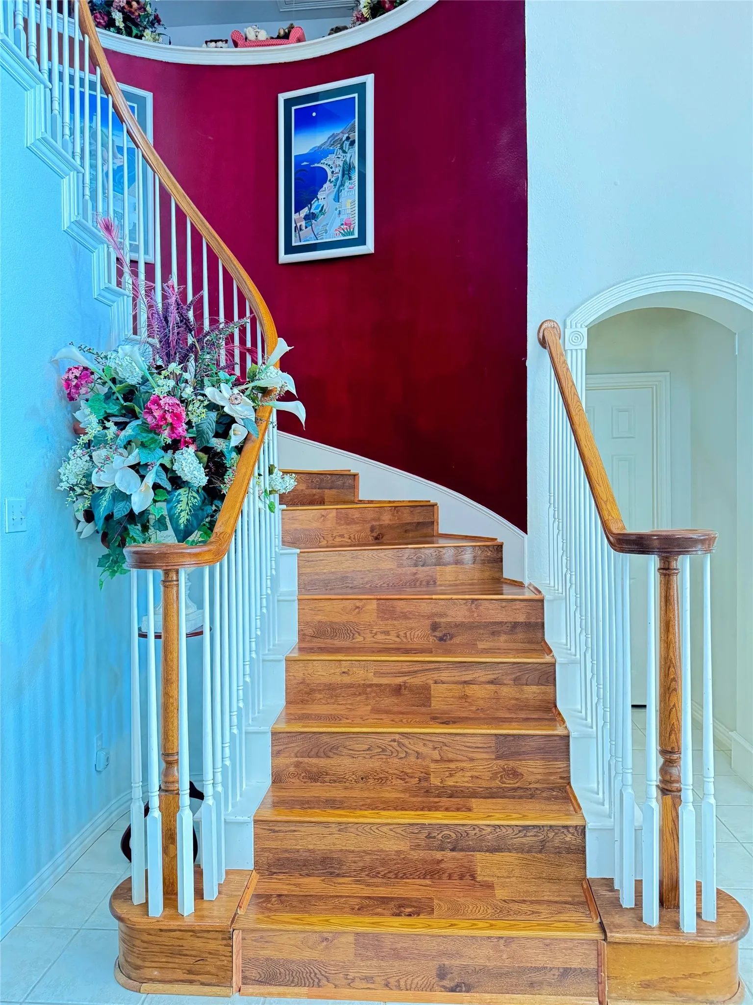 Curved staircase featuring wood-finish treads, white risers, and an elegant wood railing with white balusters